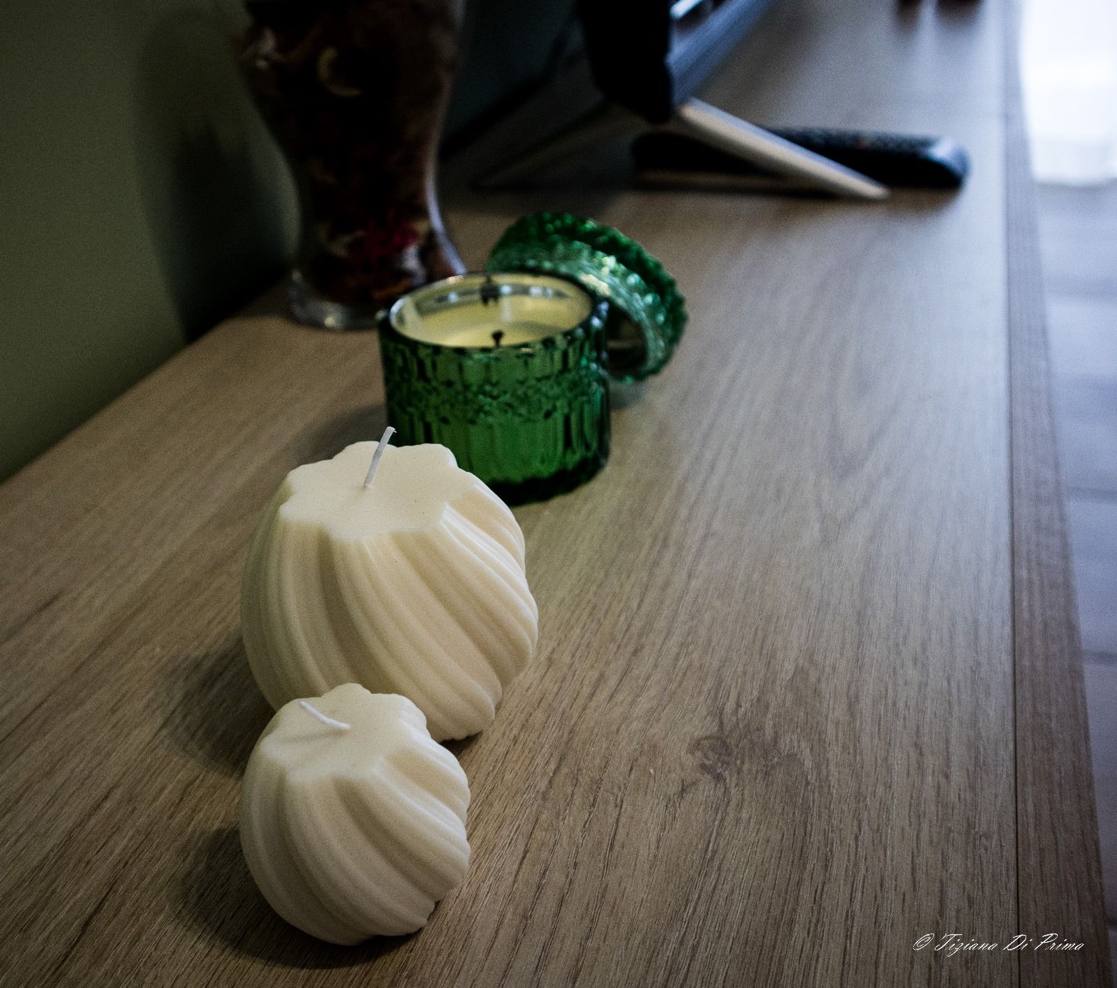 Tre candele bianche sono appoggiate su un tavolo di legno