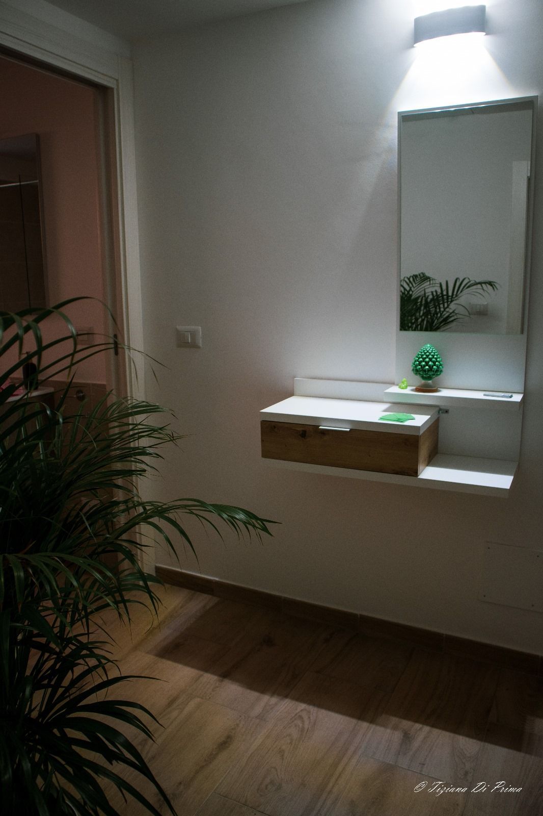 Un corridoio con uno specchio e una mensola sul muro.