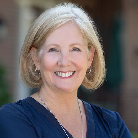 A woman in a blue shirt is smiling for the camera