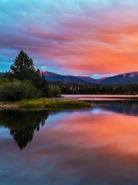 A sunset over a lake with mountains in the background