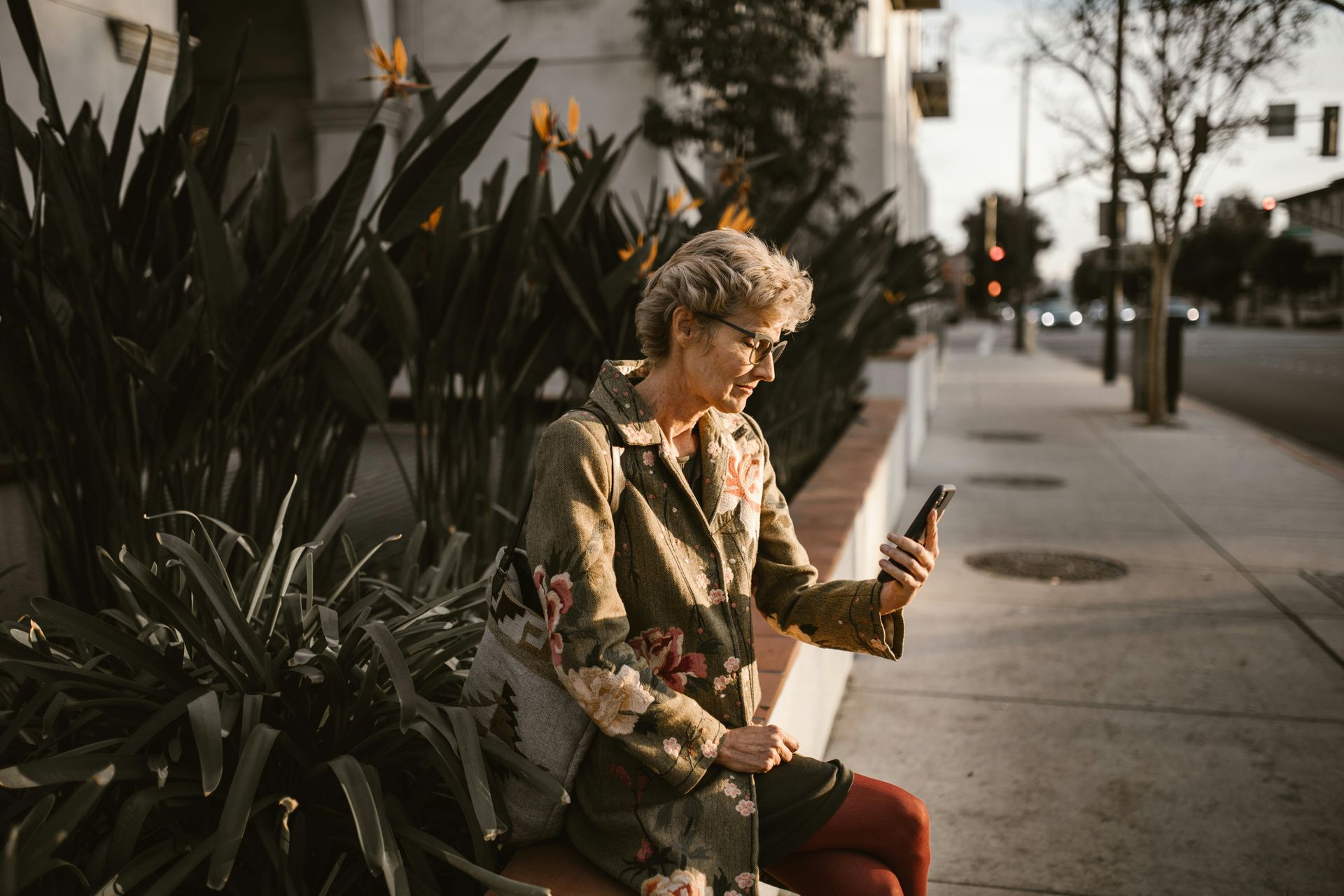 A woman is sitting on a bench looking at her cell phone.