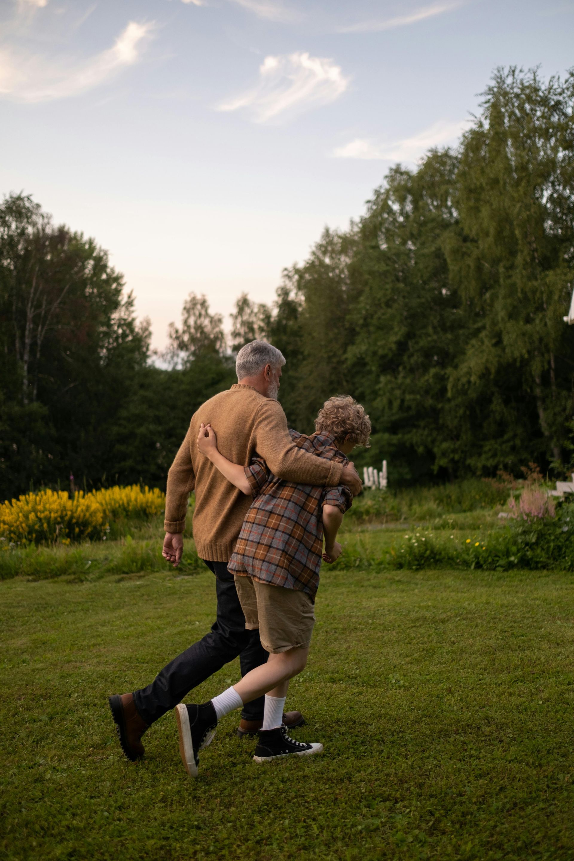A man and a boy are dancing in a field.