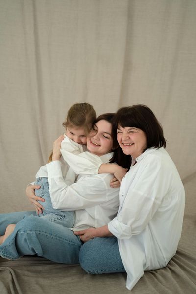 Three women are sitting on the floor hugging each other.