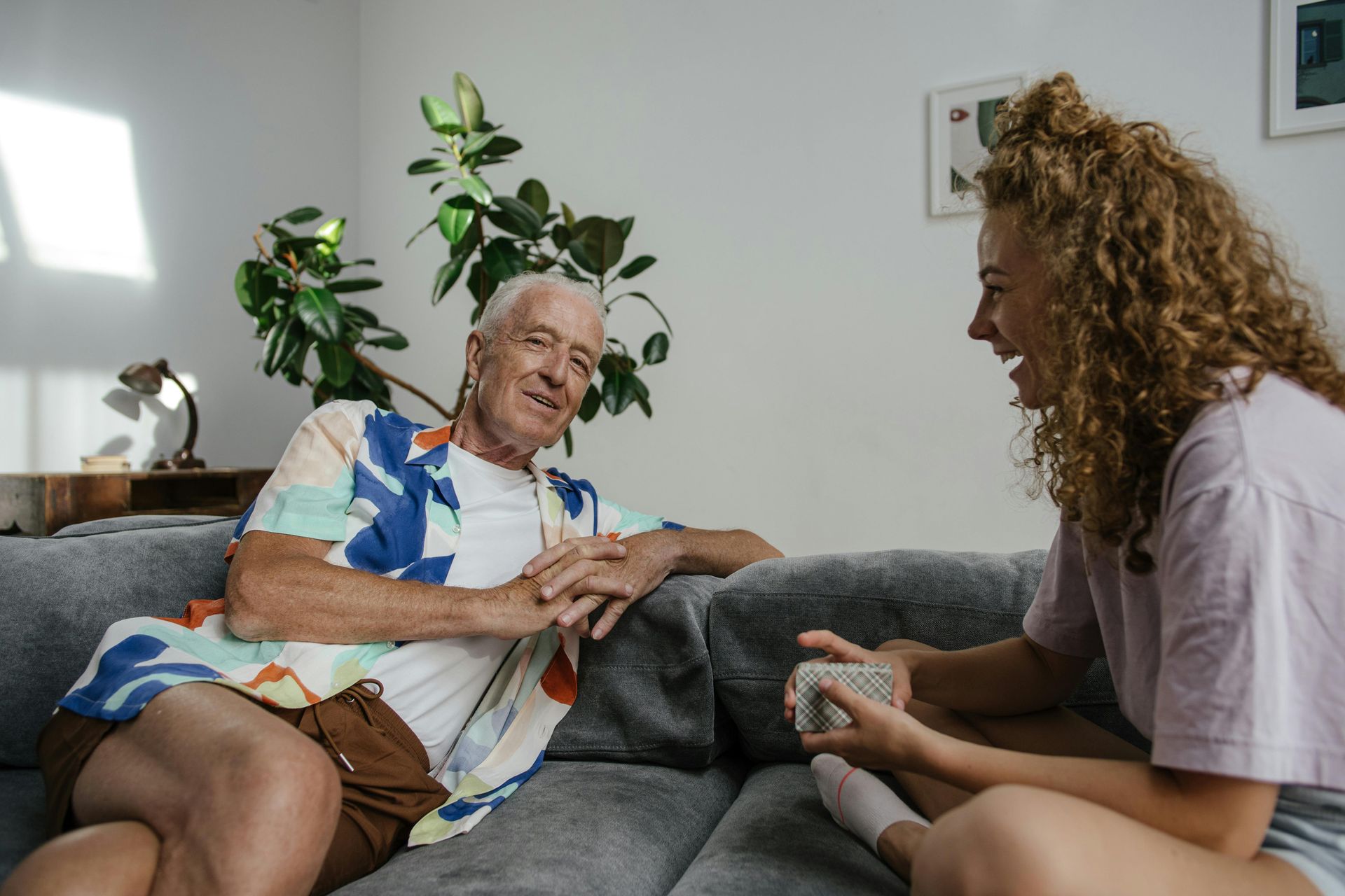 A man and a woman are sitting on a couch talking to each other.