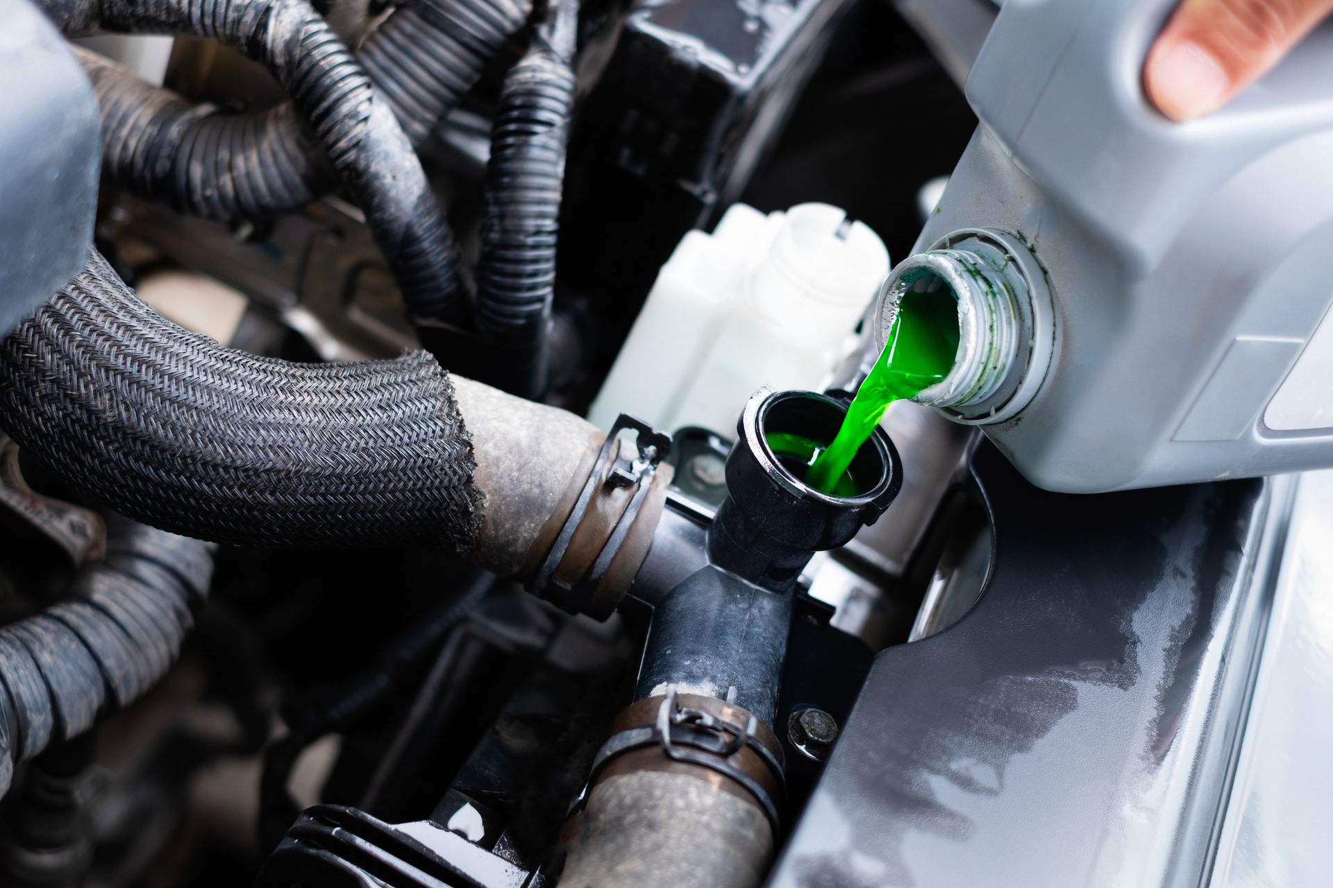 A person is pouring green coolant into a radiator of a car.