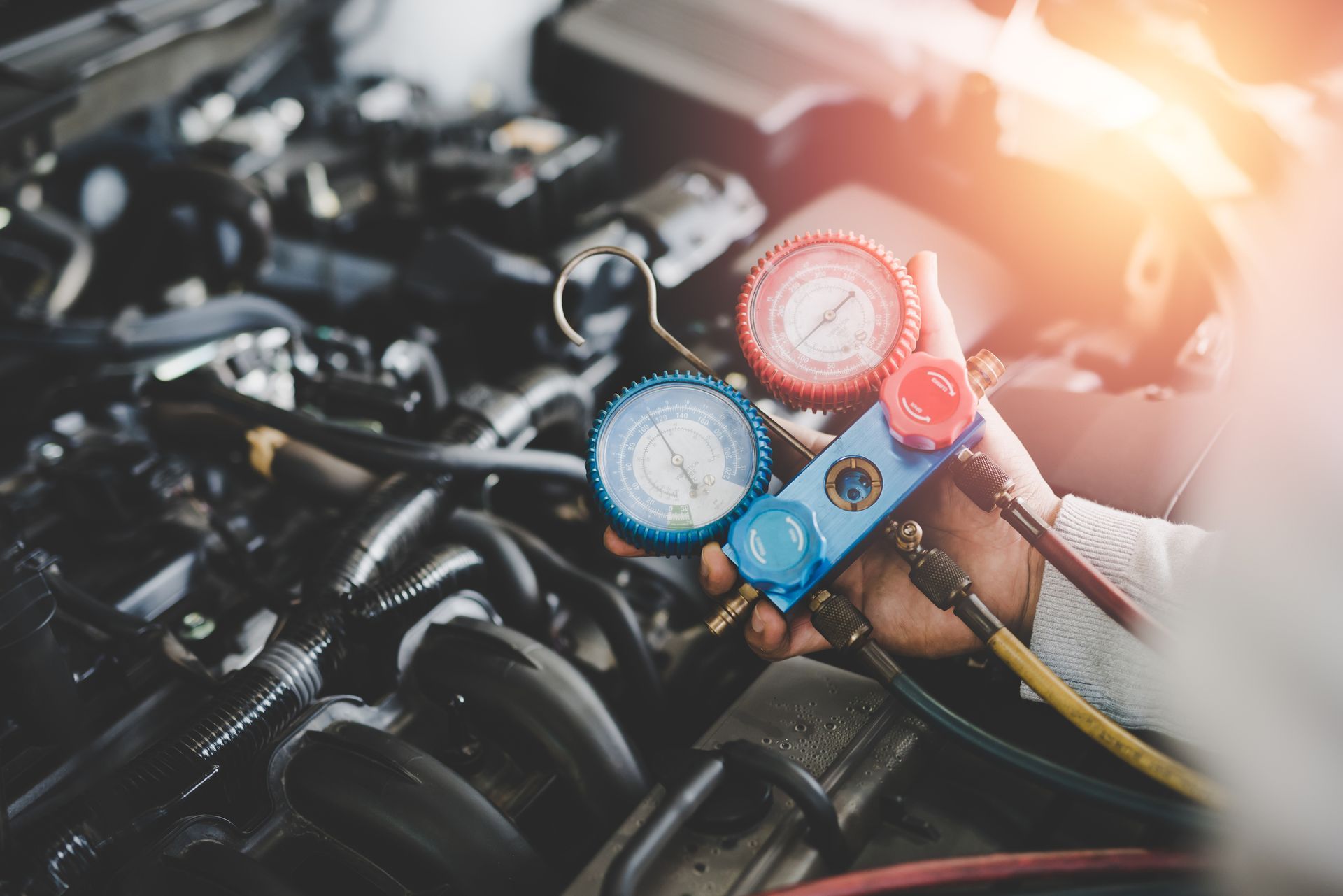 A close up of a person holding a gauge in front of a car engine.