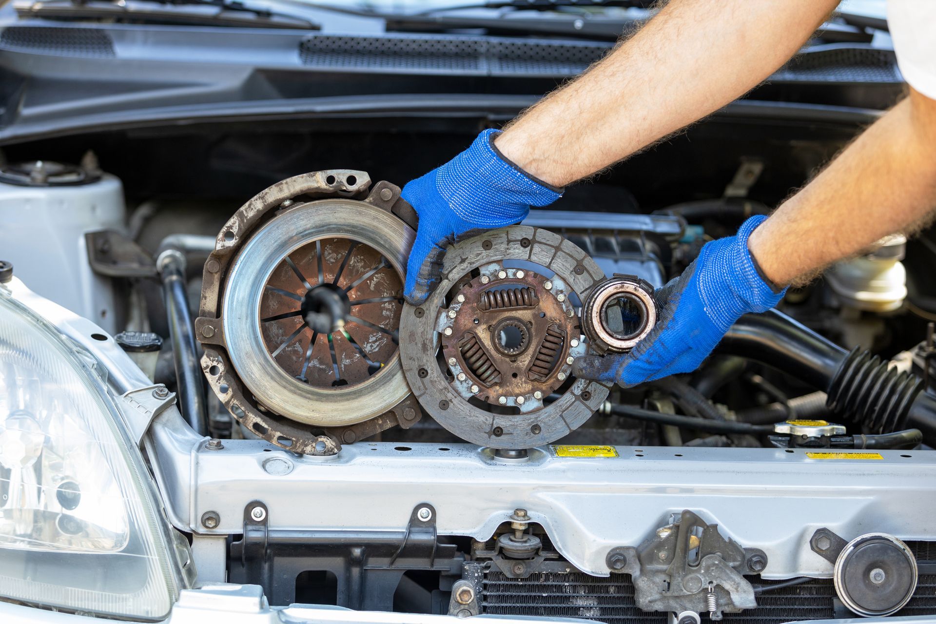 A man is working on the clutch on a car.