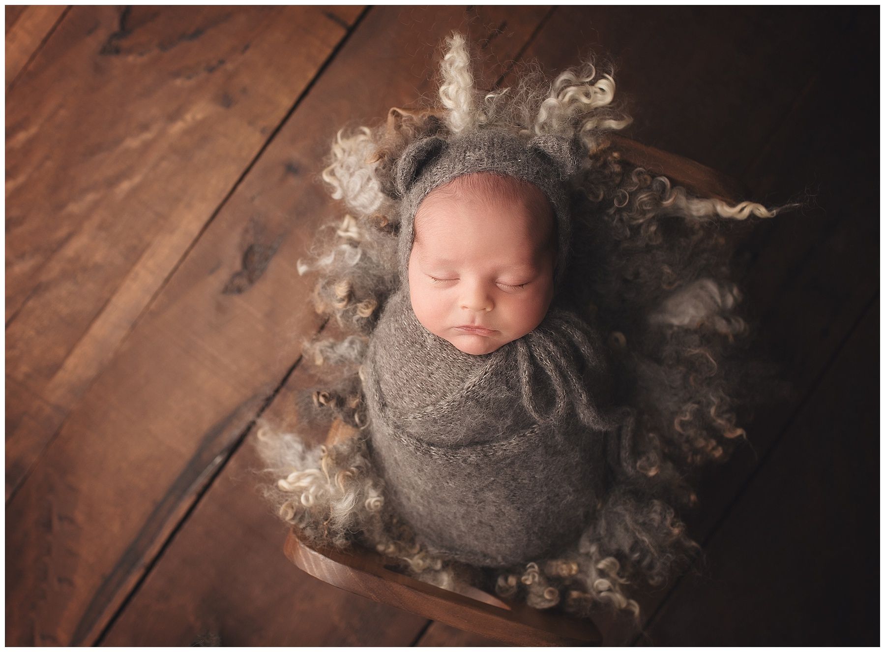 A newborn baby is wrapped in a blanket and wearing a hat.