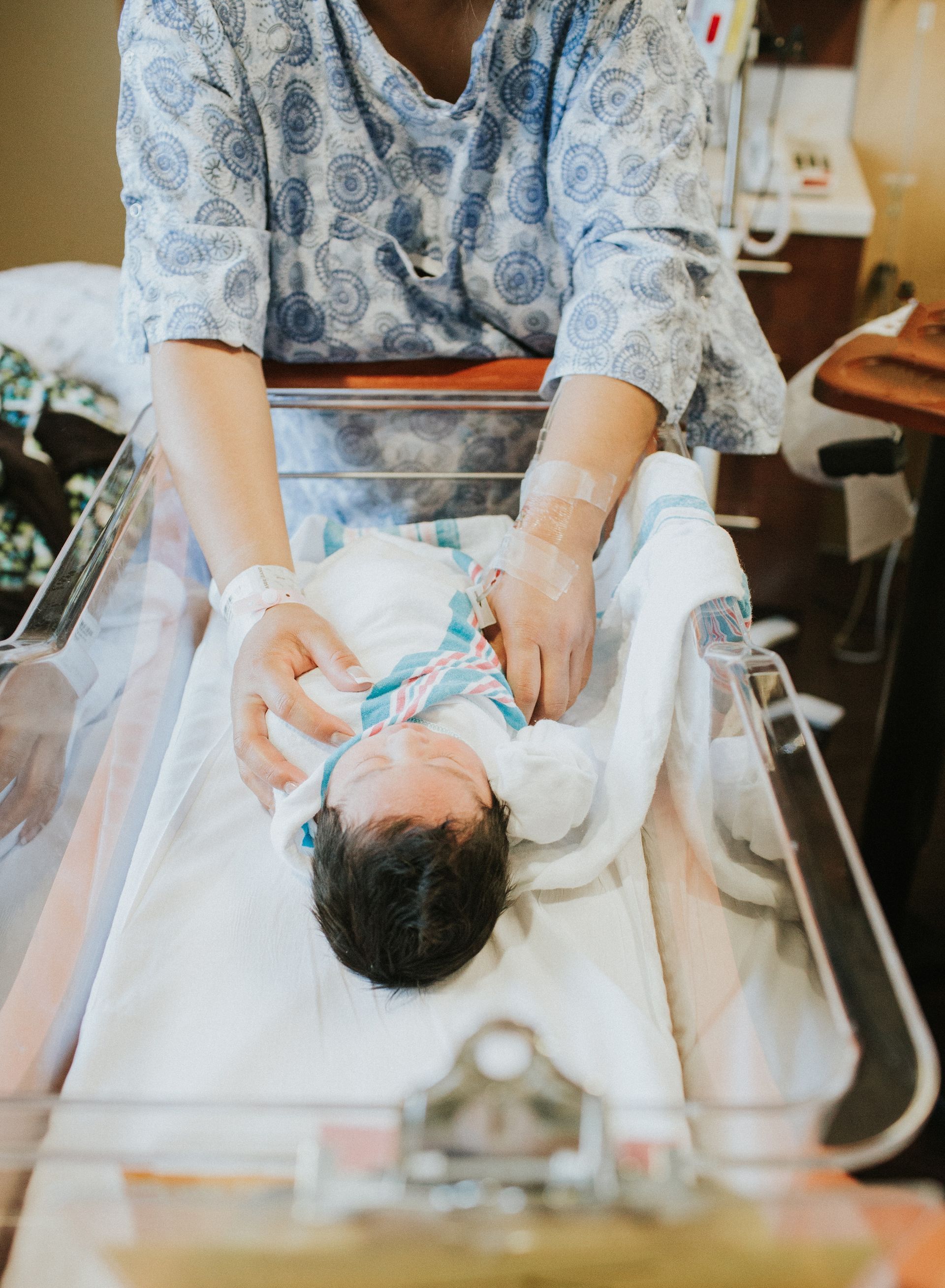 A woman is holding a newborn baby in a hospital crib.