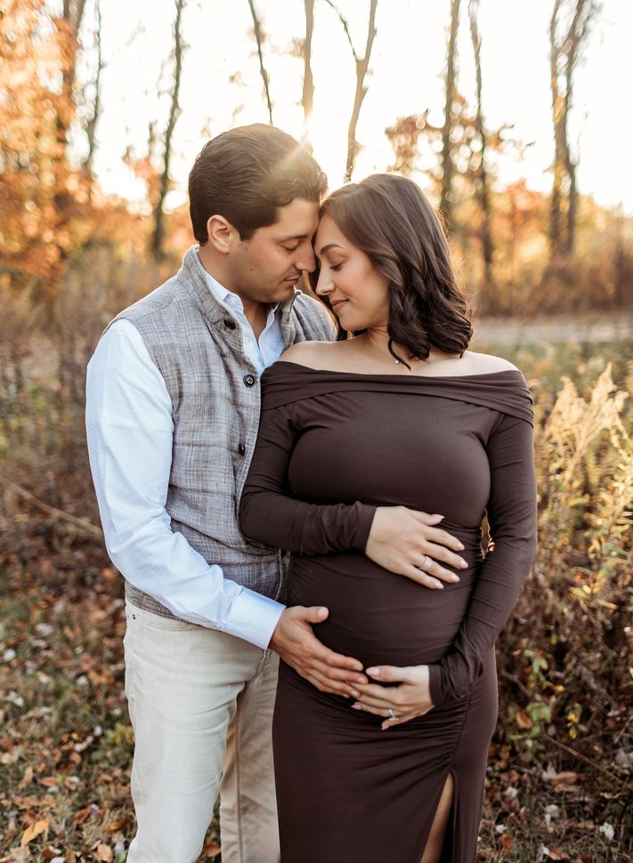 Pregnant couple embraces outdoors; man holds woman's belly in Bergen County, NJ