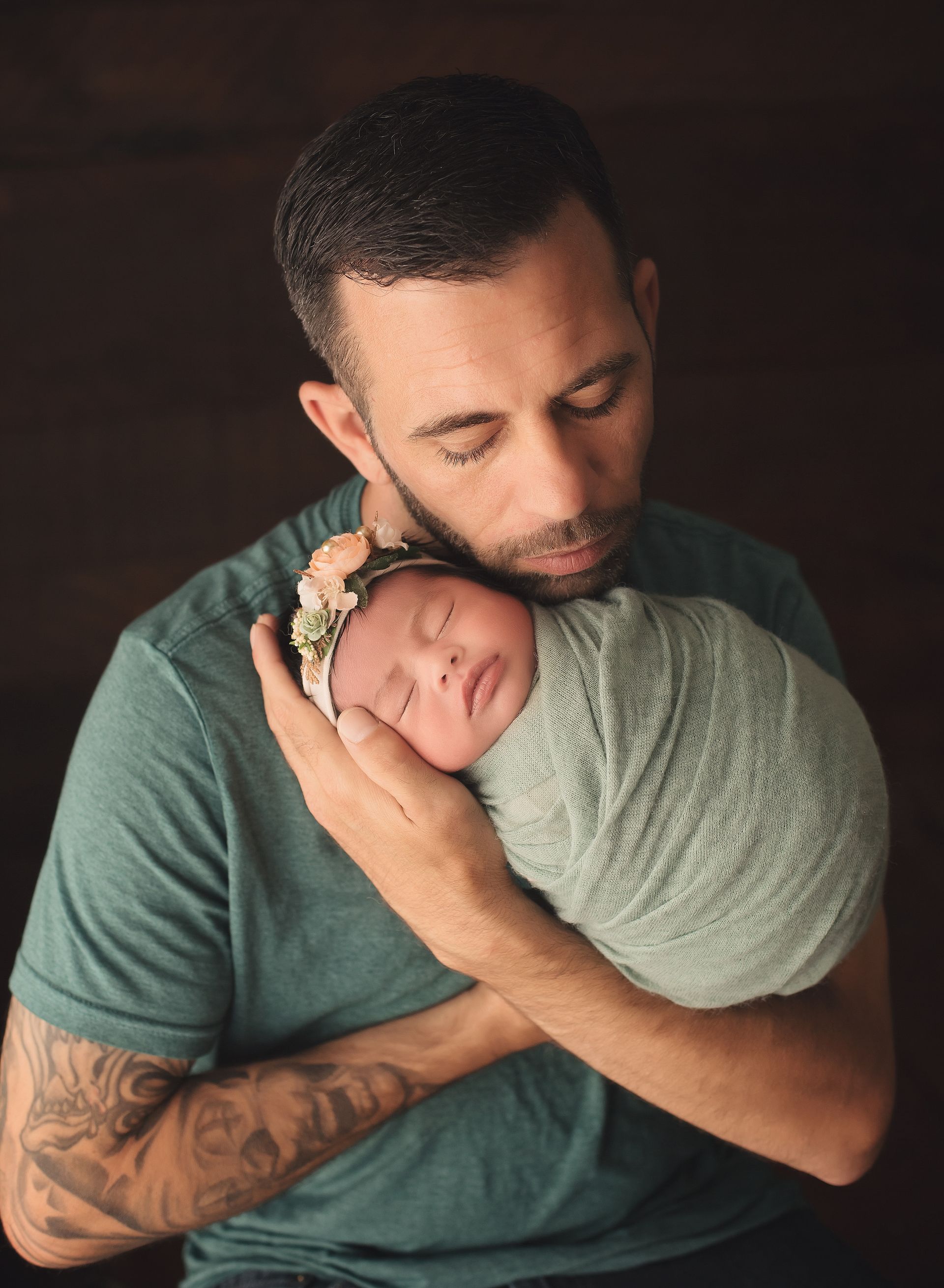 A man is holding a newborn baby wrapped in a blanket.
