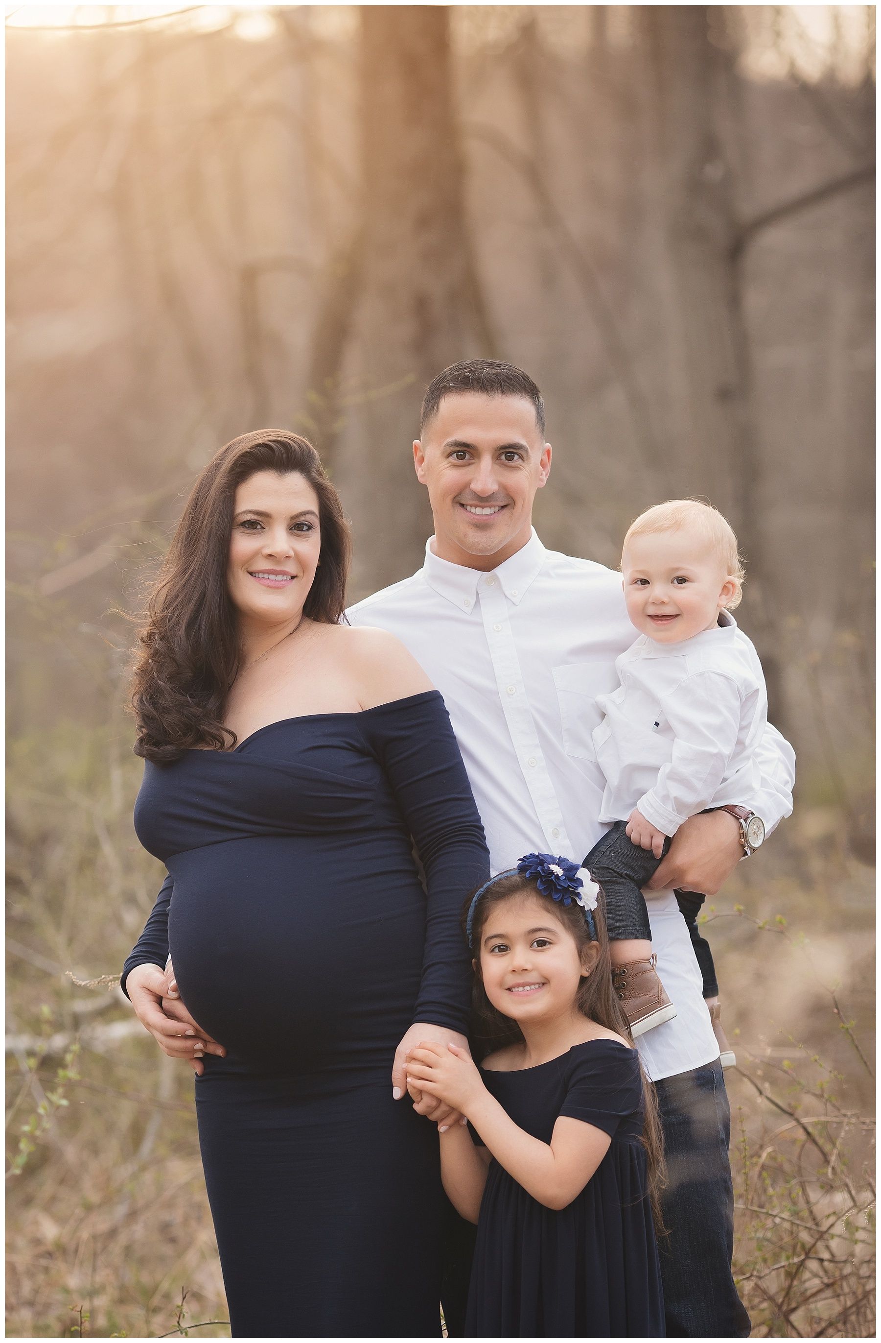 A pregnant woman is posing for a picture with her husband and two children.