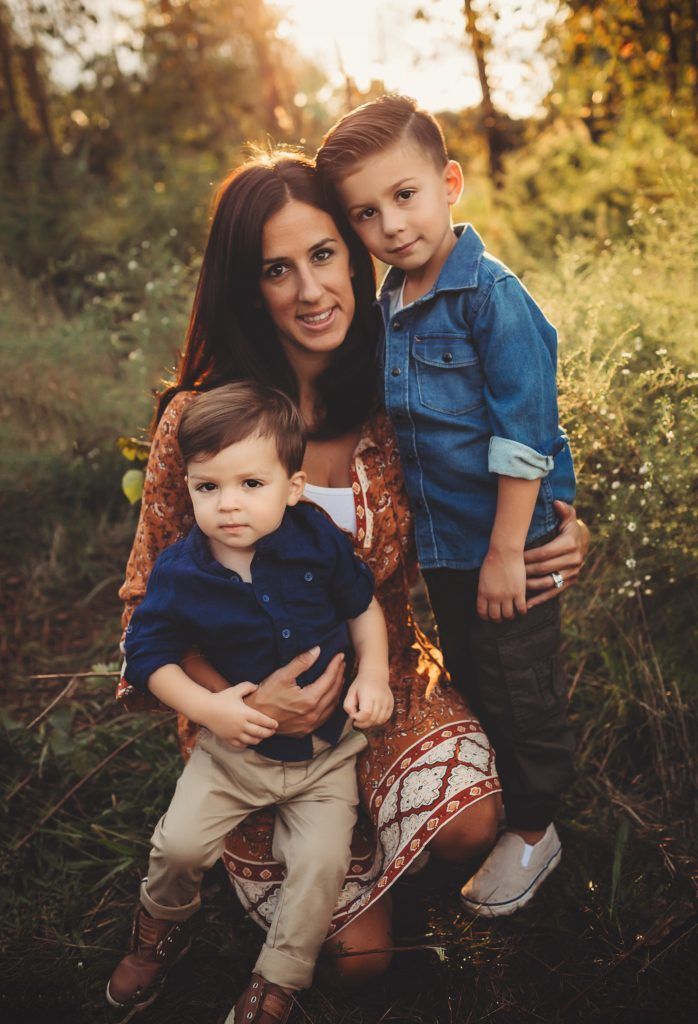 A woman is holding two children in her arms in a field.