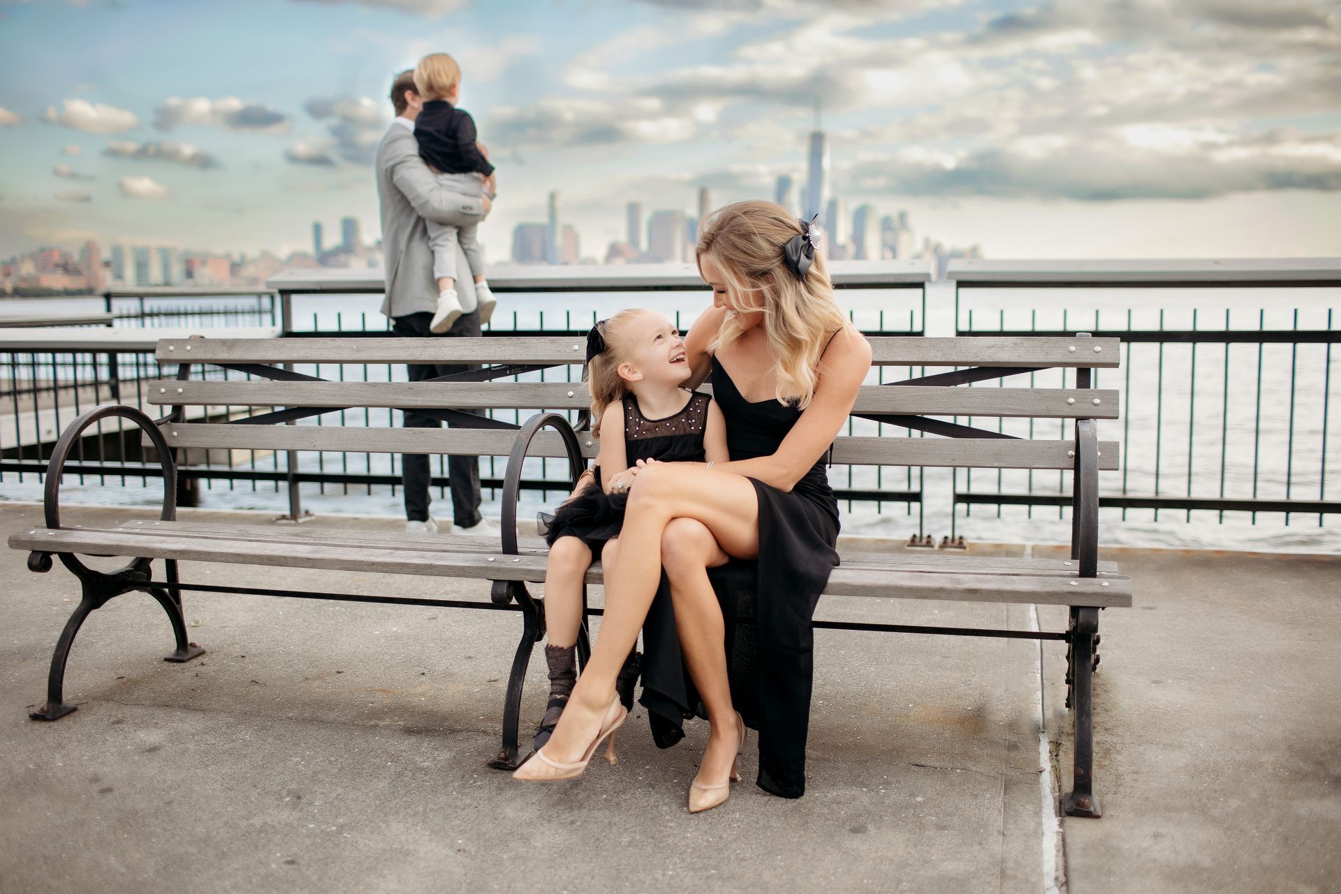 A woman and a child are sitting on a park bench.