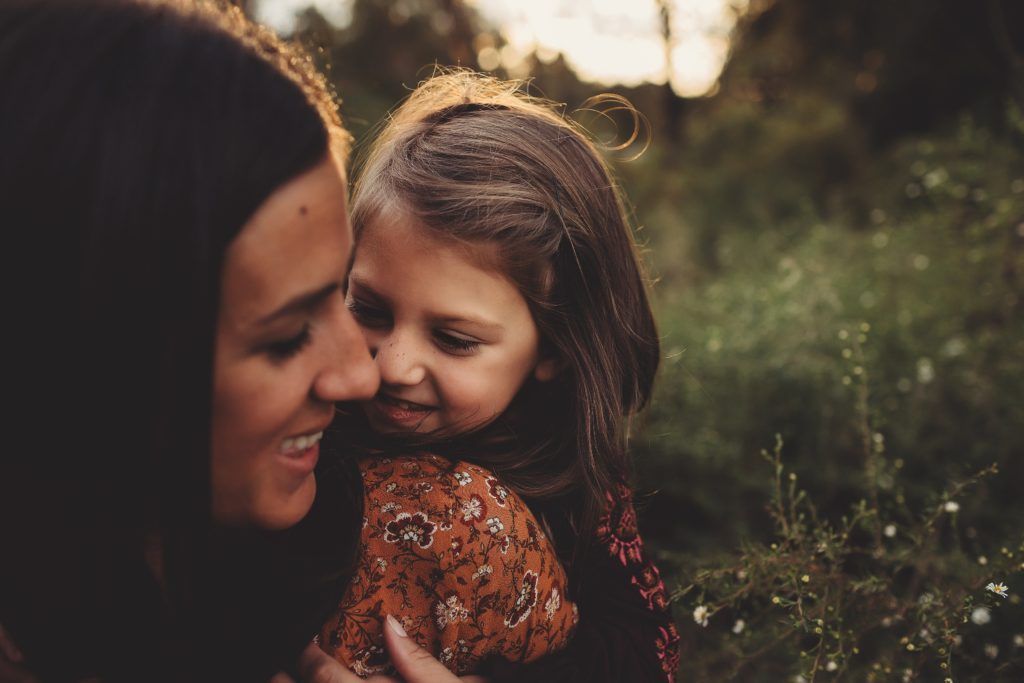 A woman is holding a little girl in her arms in a field.