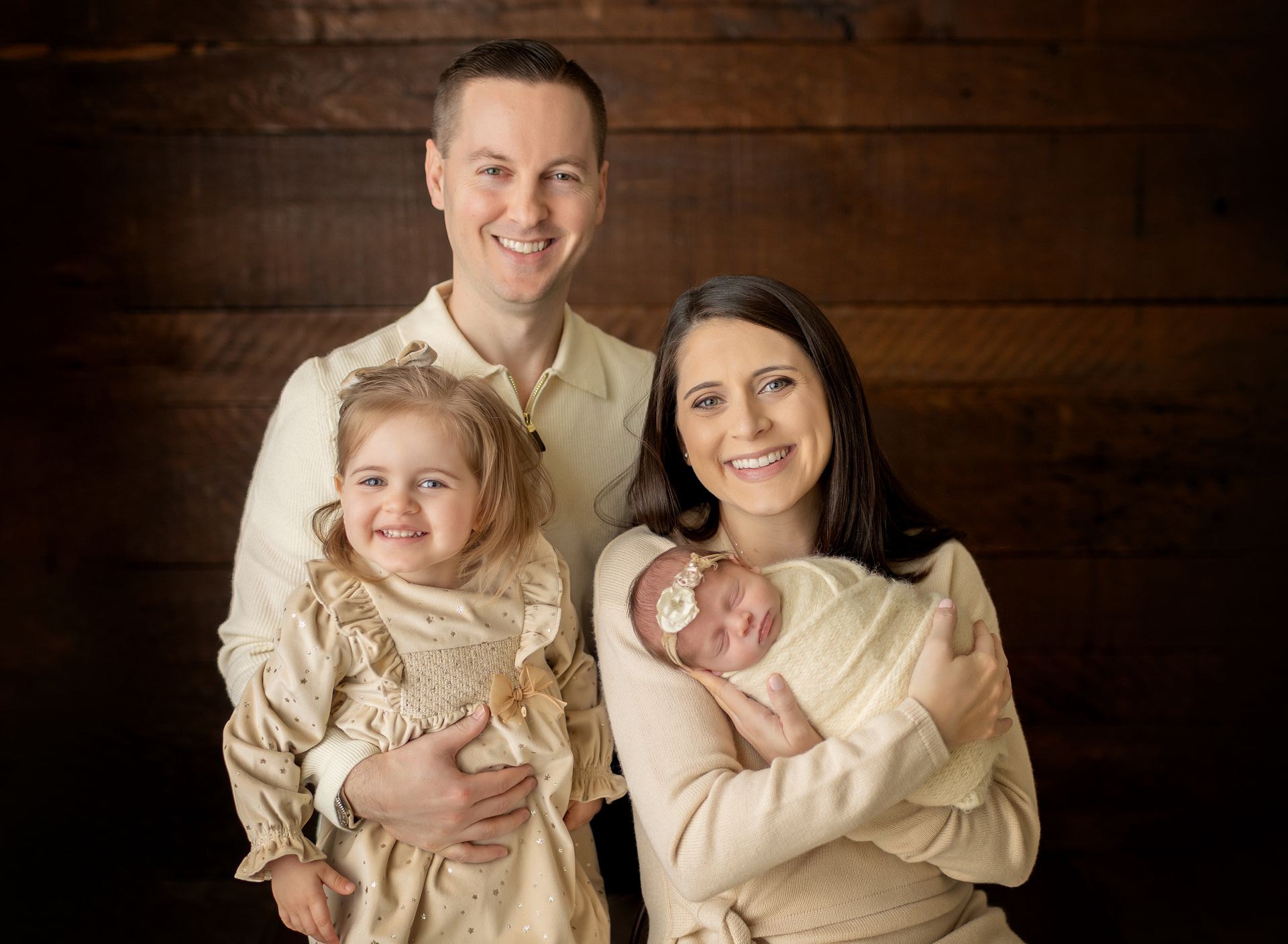 A family is posing for a picture with a newborn baby.