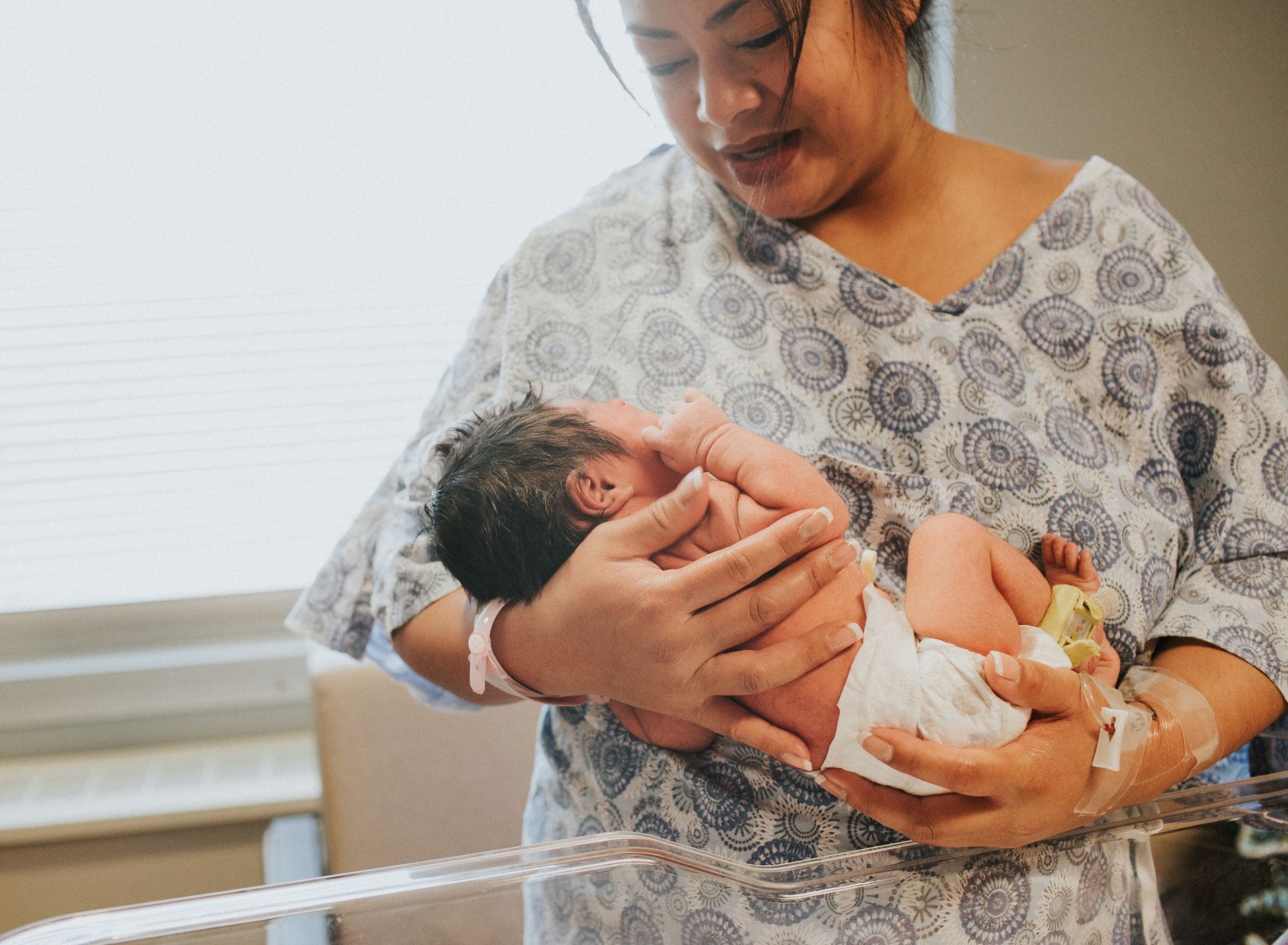 A woman is holding a newborn baby in her arms in a hospital room.