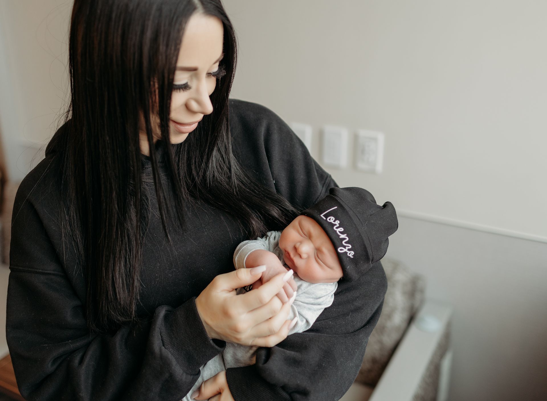 A woman is holding a newborn baby in her arms in hospital room.