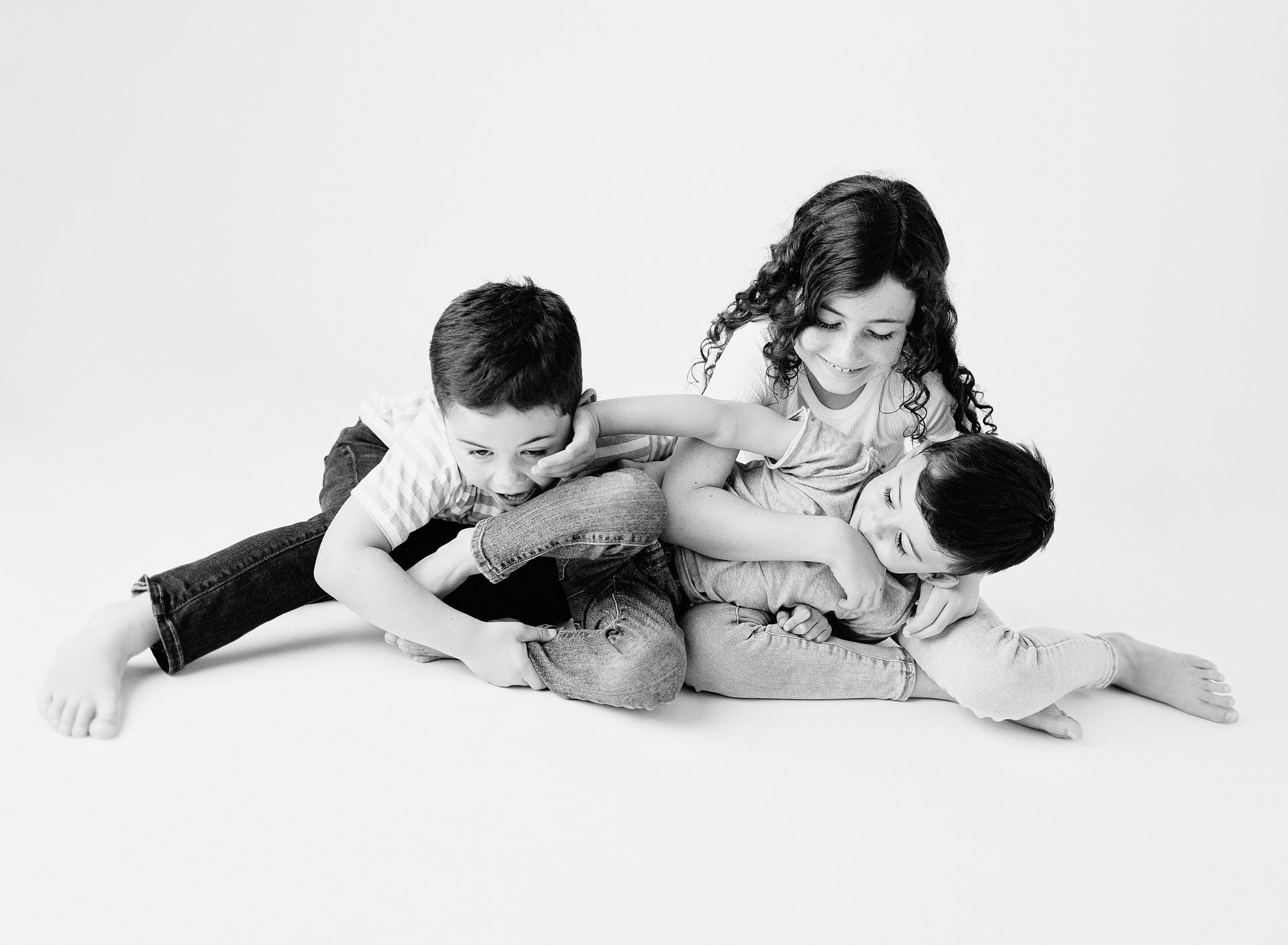 Three children playfully interacting against a white backdrop.
