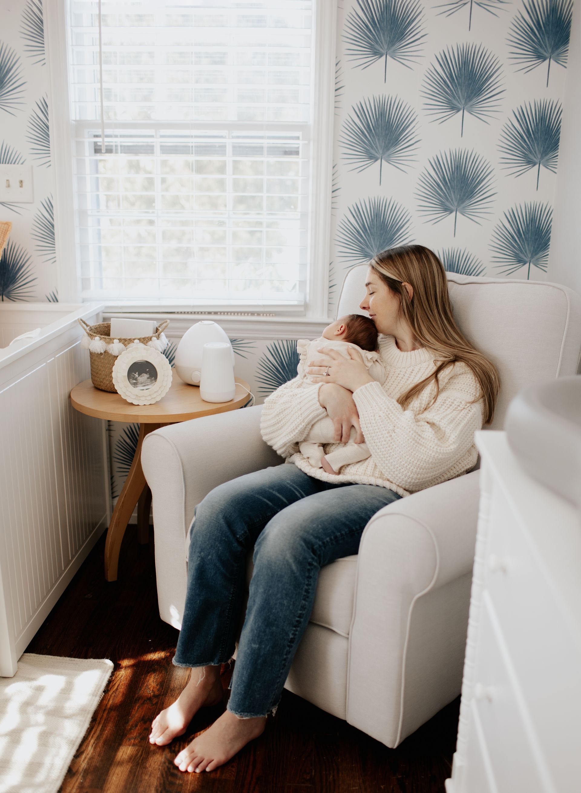 A mother is sitting in a chair holding a baby in a nursery.