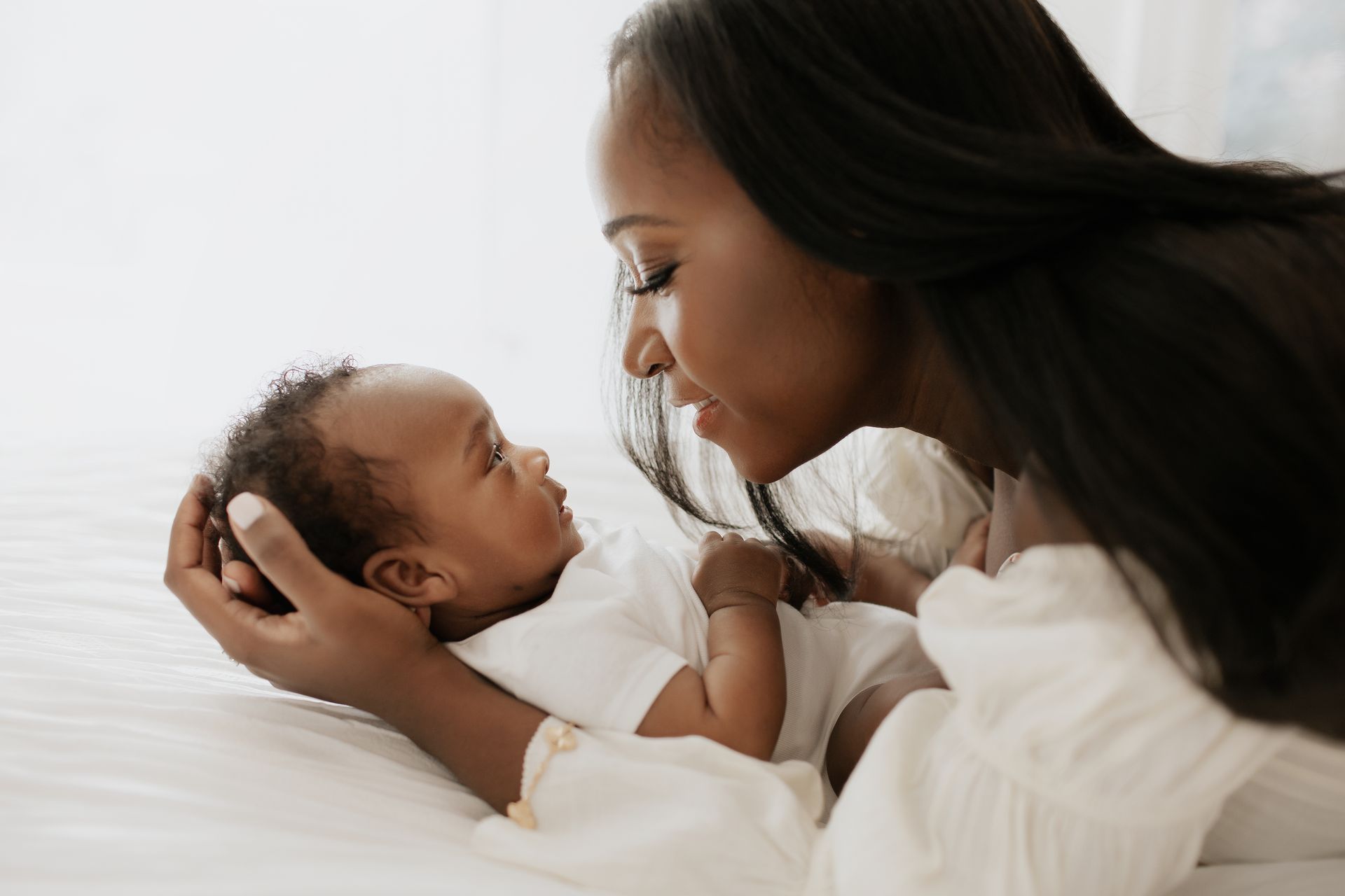 A woman is holding a baby in her arms on a bed.