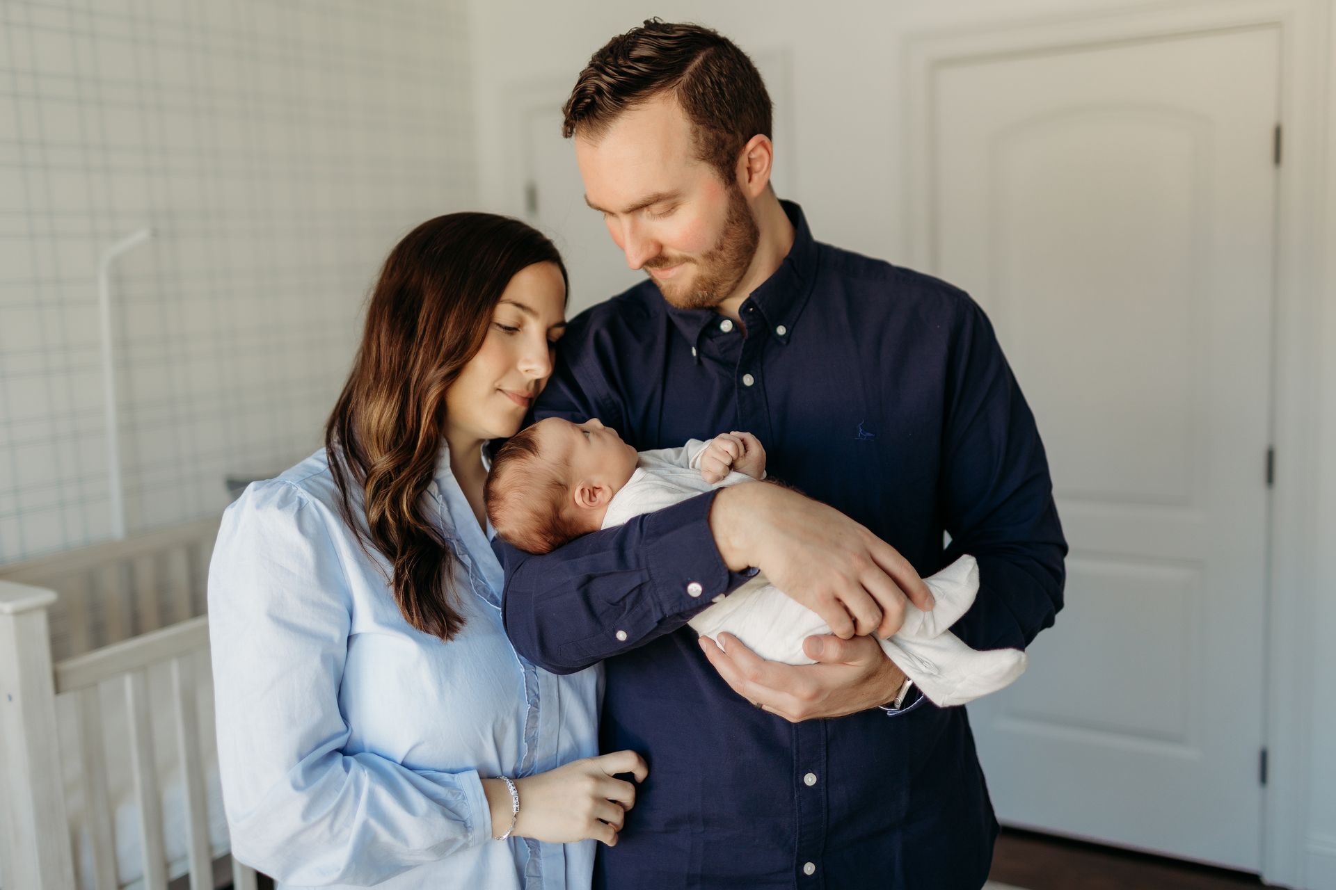 A man and woman are holding their baby in the nursery.