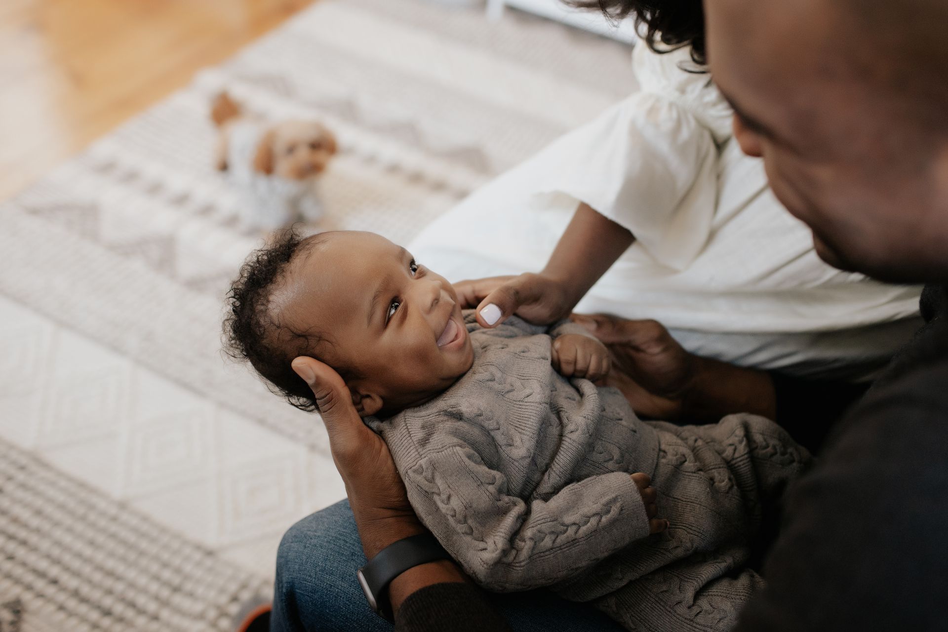 A man is holding a baby in his lap and the baby is smiling.