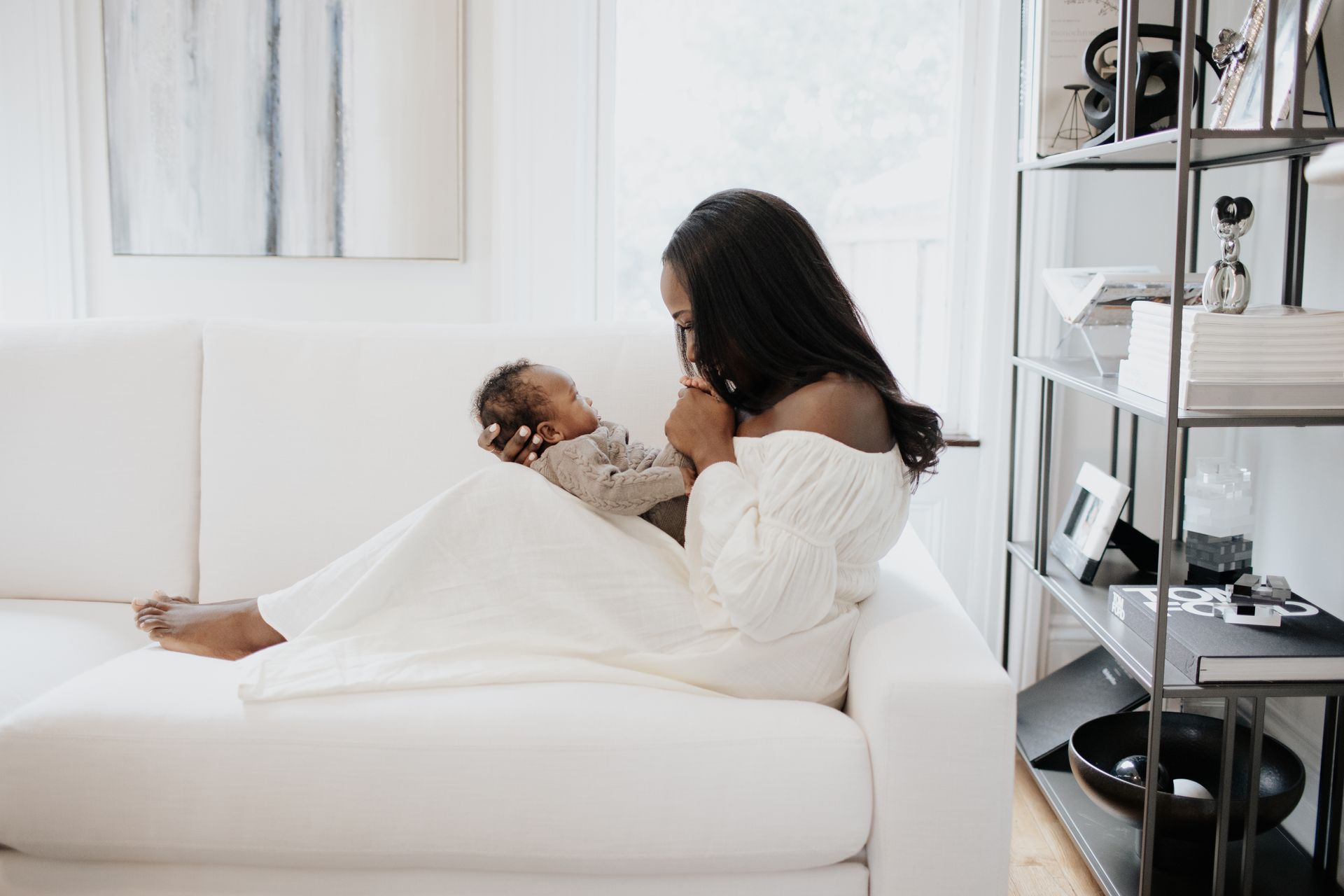 A woman is sitting on a couch holding a baby.