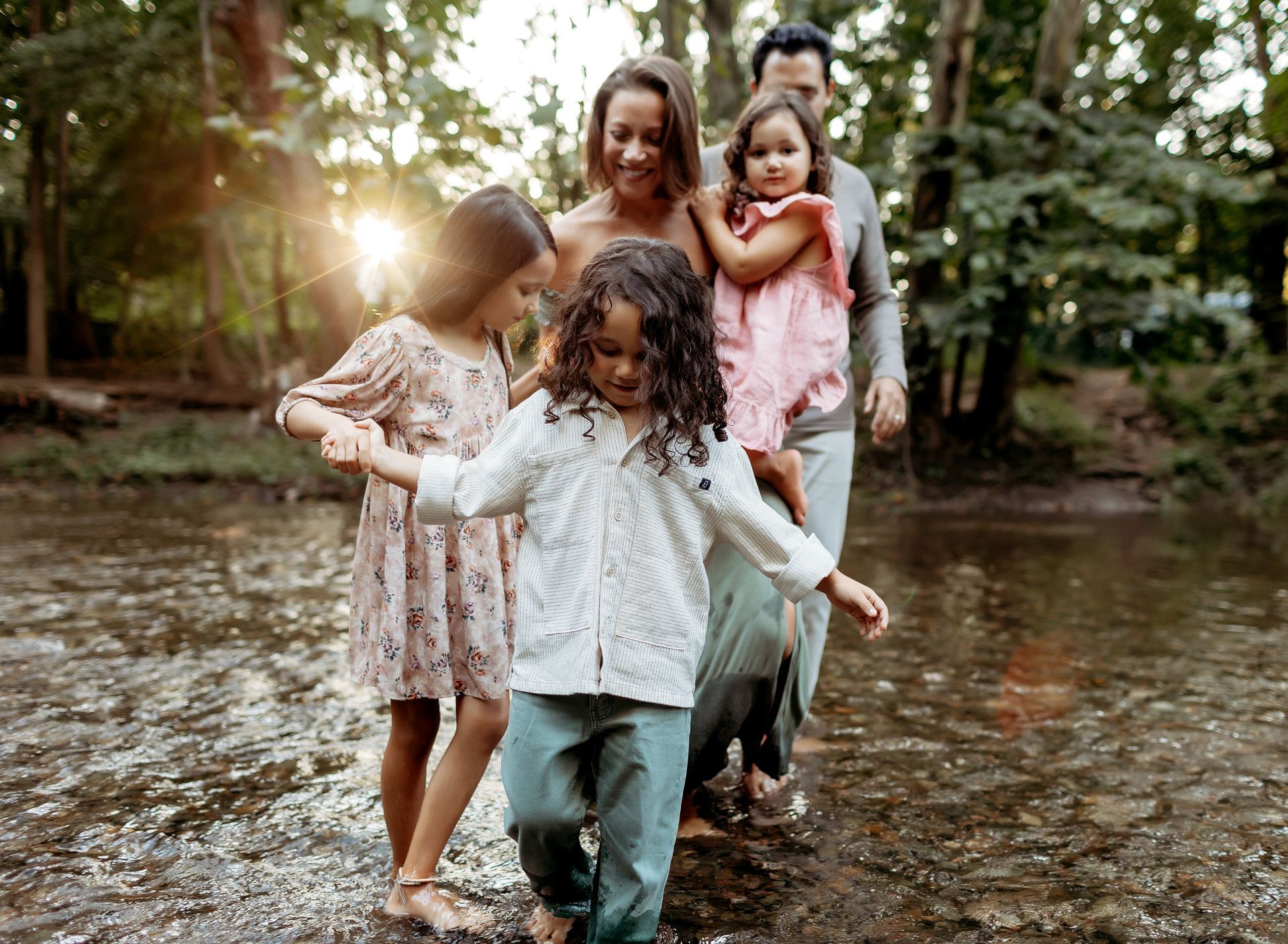 A family is walking through a stream in the woods.