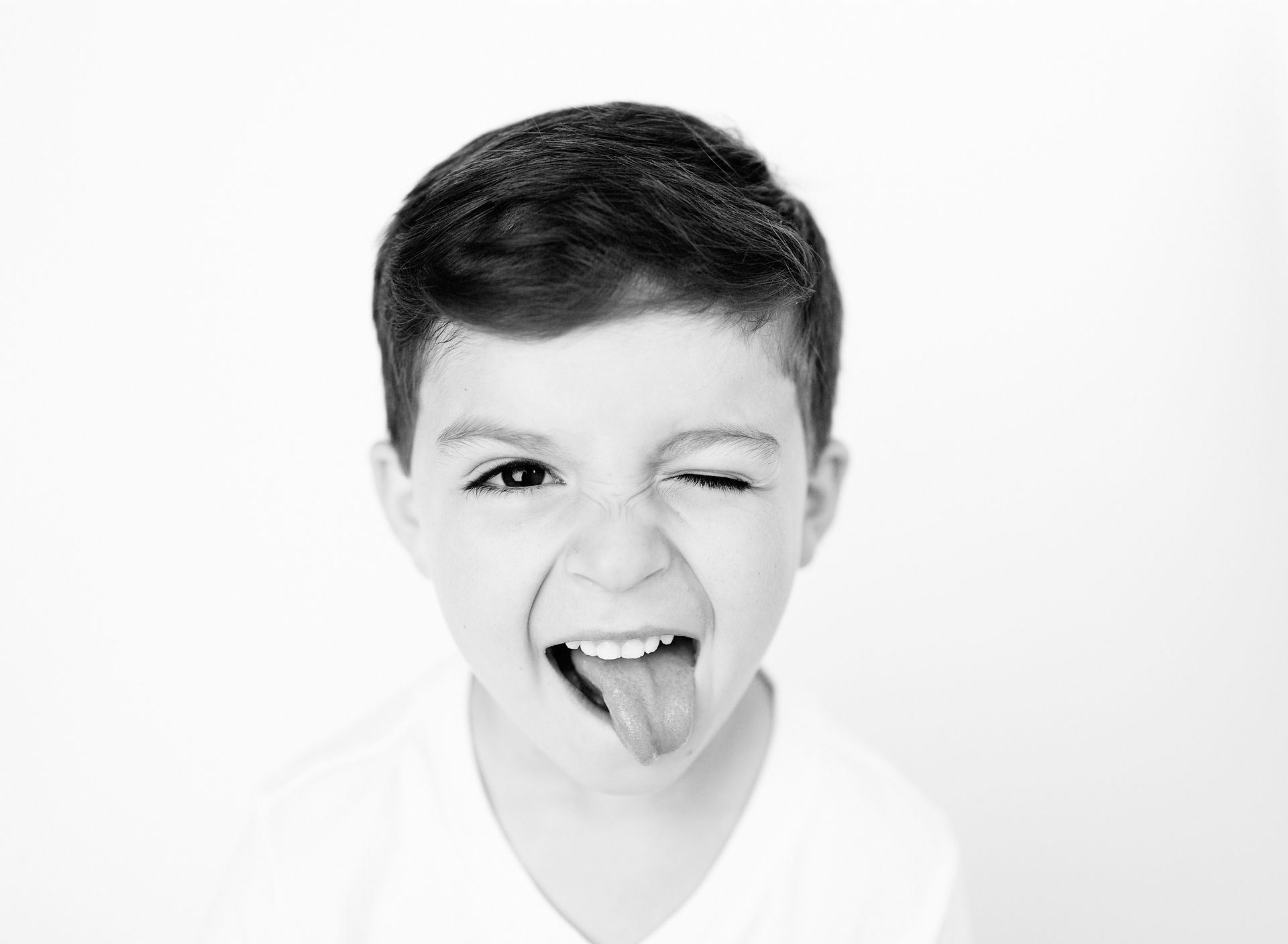 Boy winking, sticking out tongue, making a funny face in black and white.