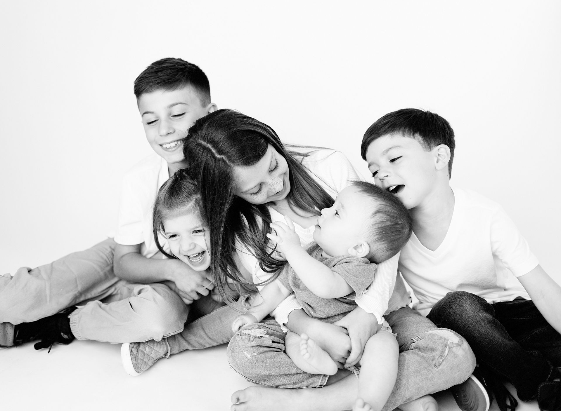 Group of children laughing and interacting, in a studio setting. Black and white.