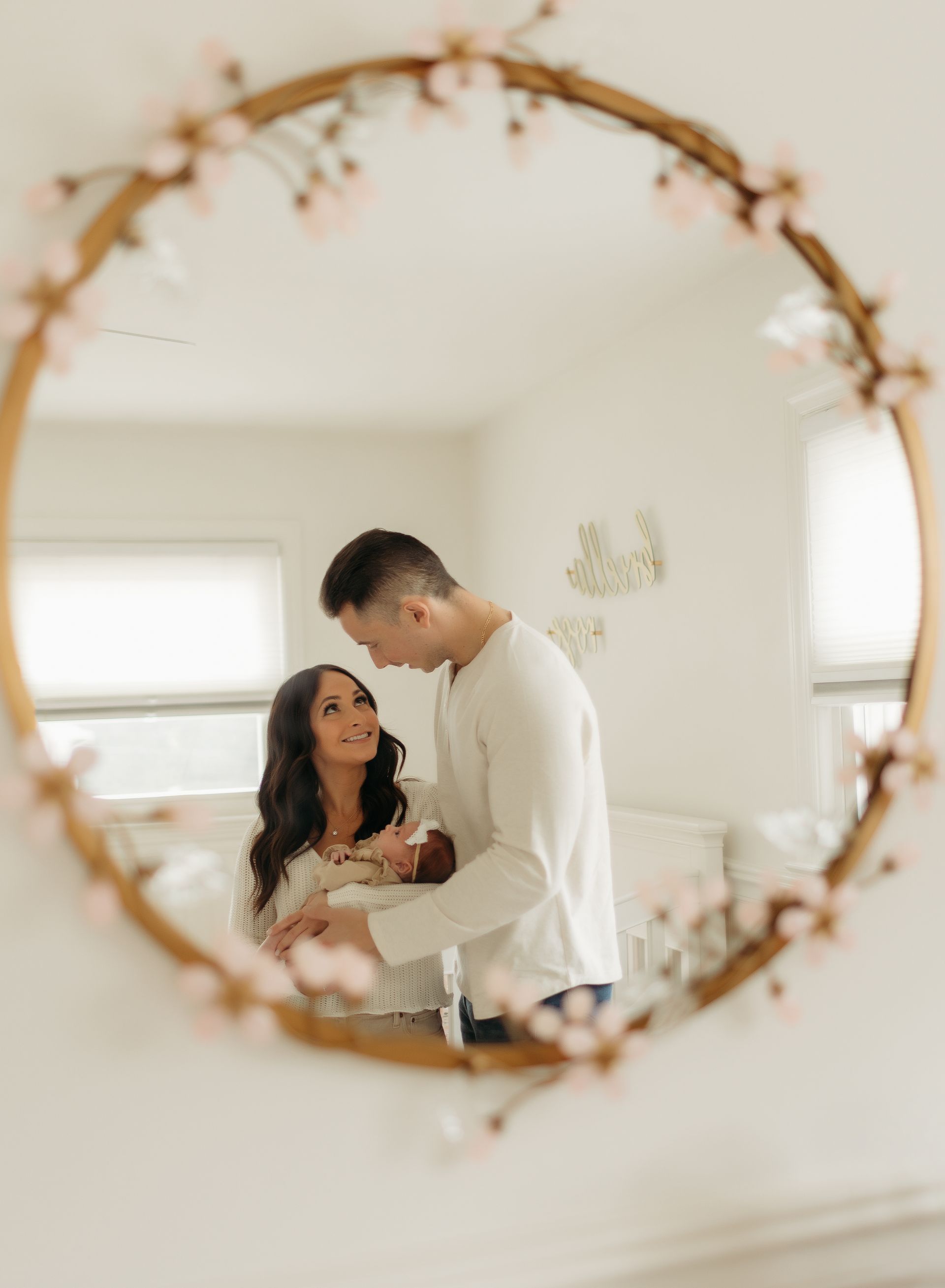 A man and woman are holding a baby in front of a mirror.