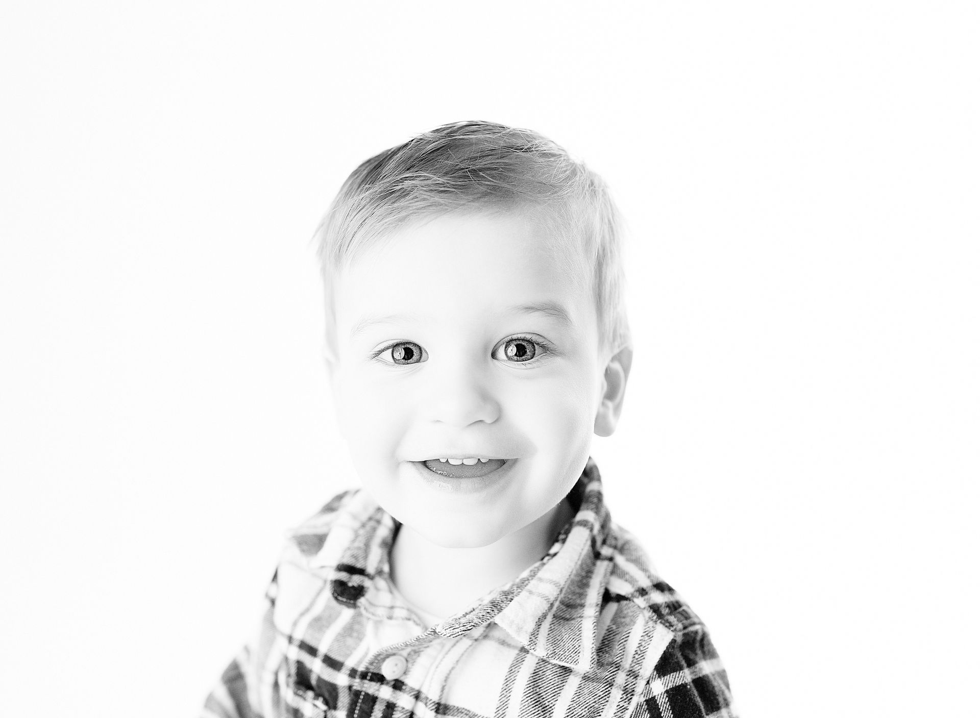 Smiling child in plaid shirt, against a white background.