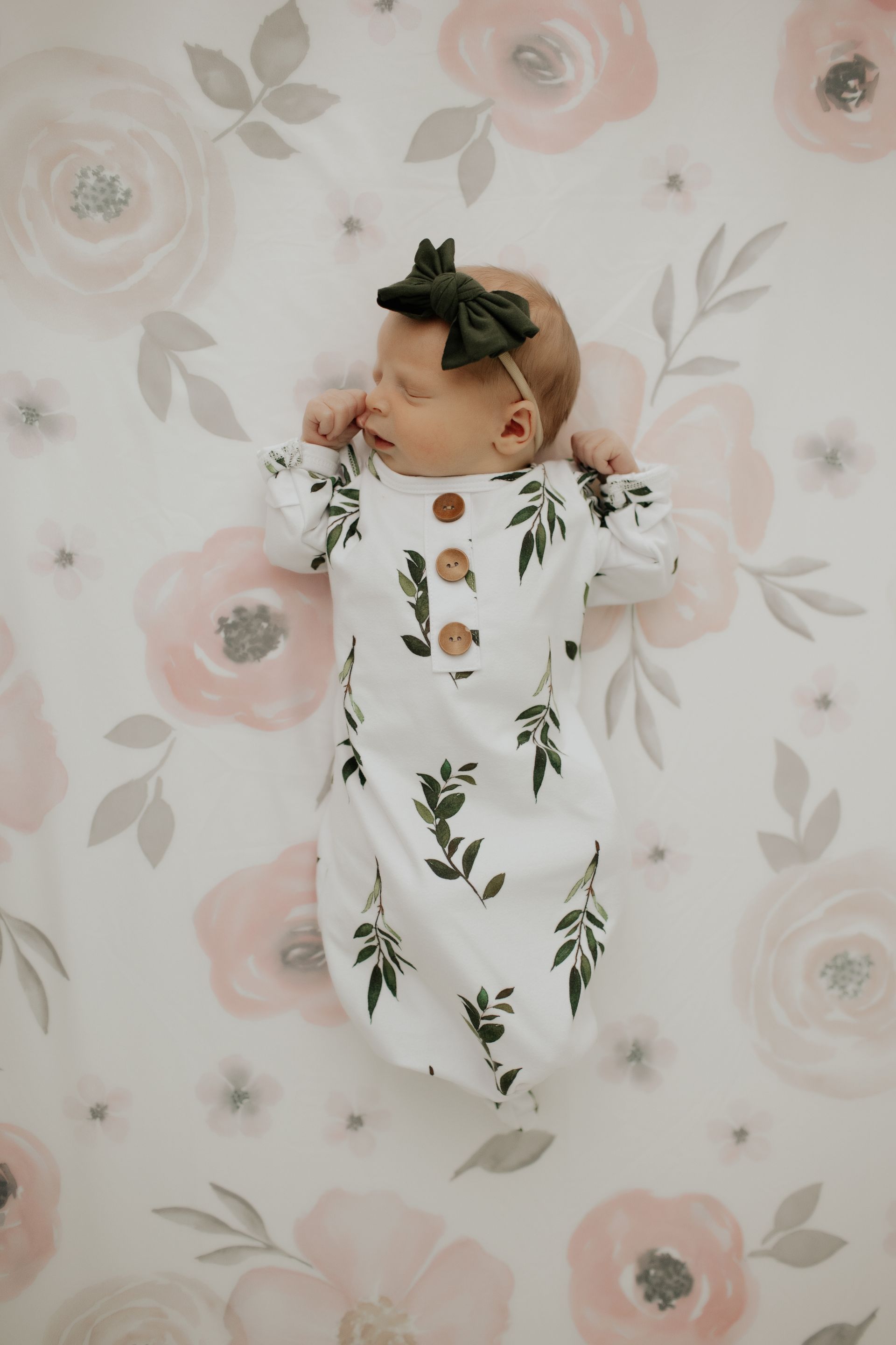 A newborn baby is laying on a floral blanket in her crib.
