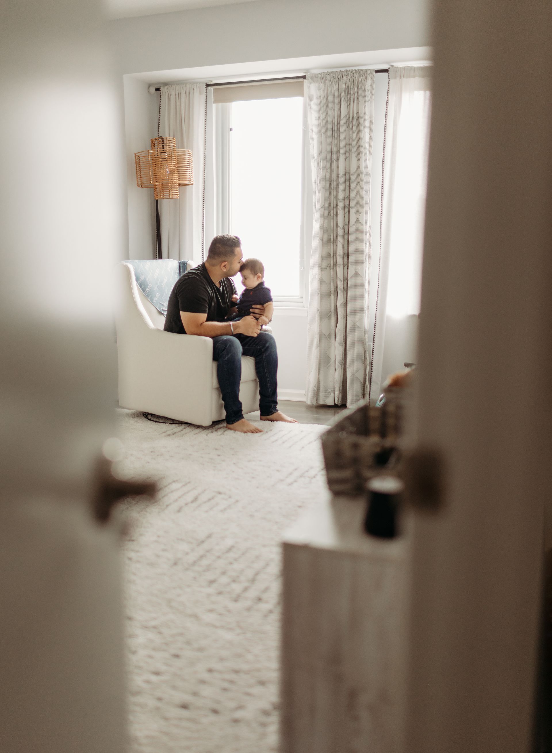 A man is sitting in a chair holding a baby in a nursery.