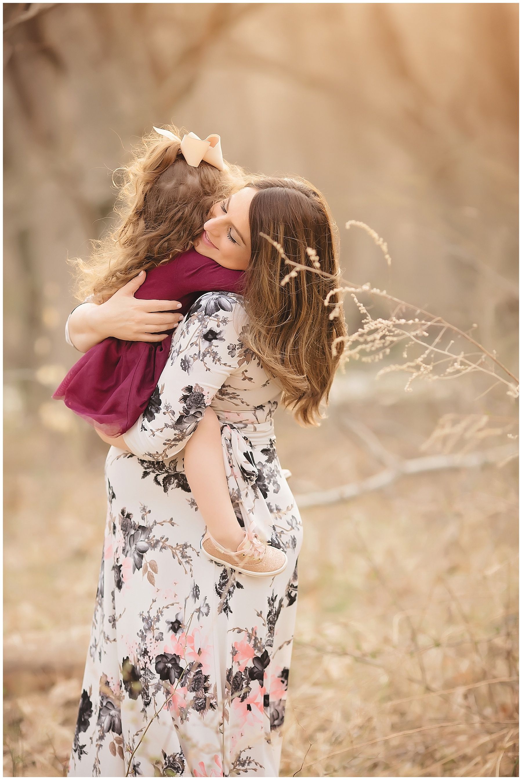 A woman is holding a little girl in her arms in a field.