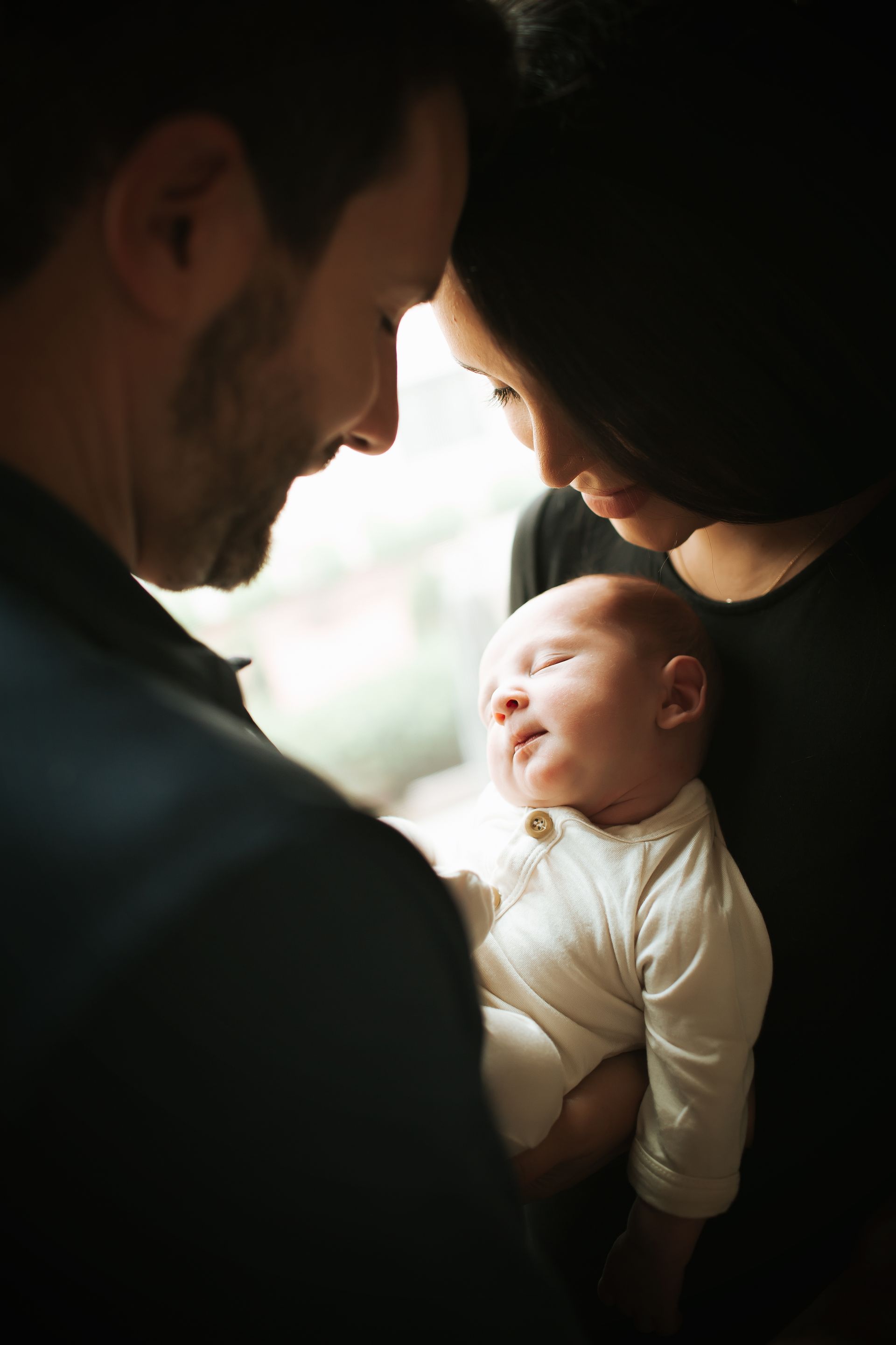A man and woman are holding a newborn baby in their arms.