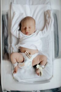 A newborn baby is sleeping in a hospital bed.