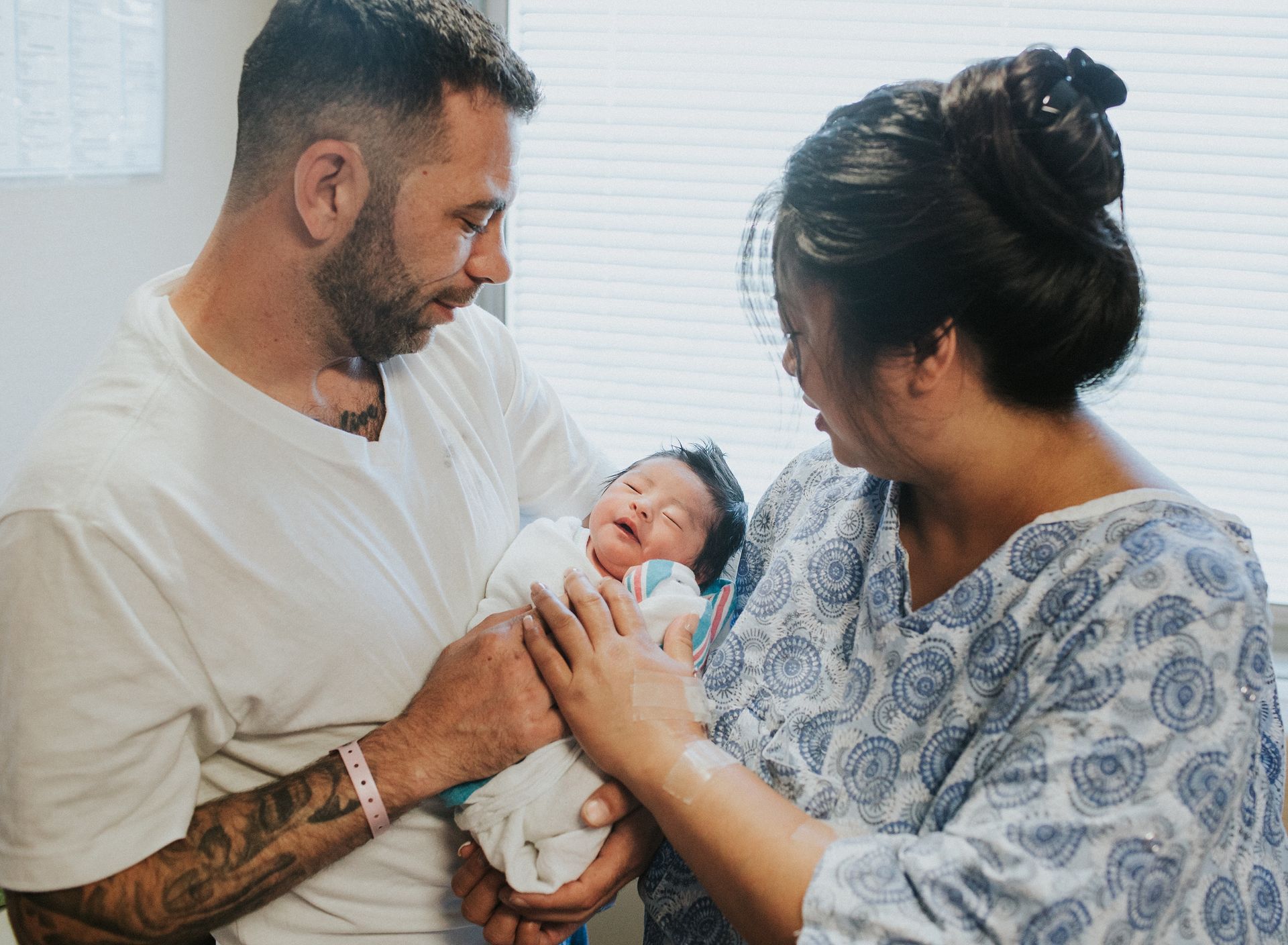 A man and woman are holding a newborn baby in a hospital room.