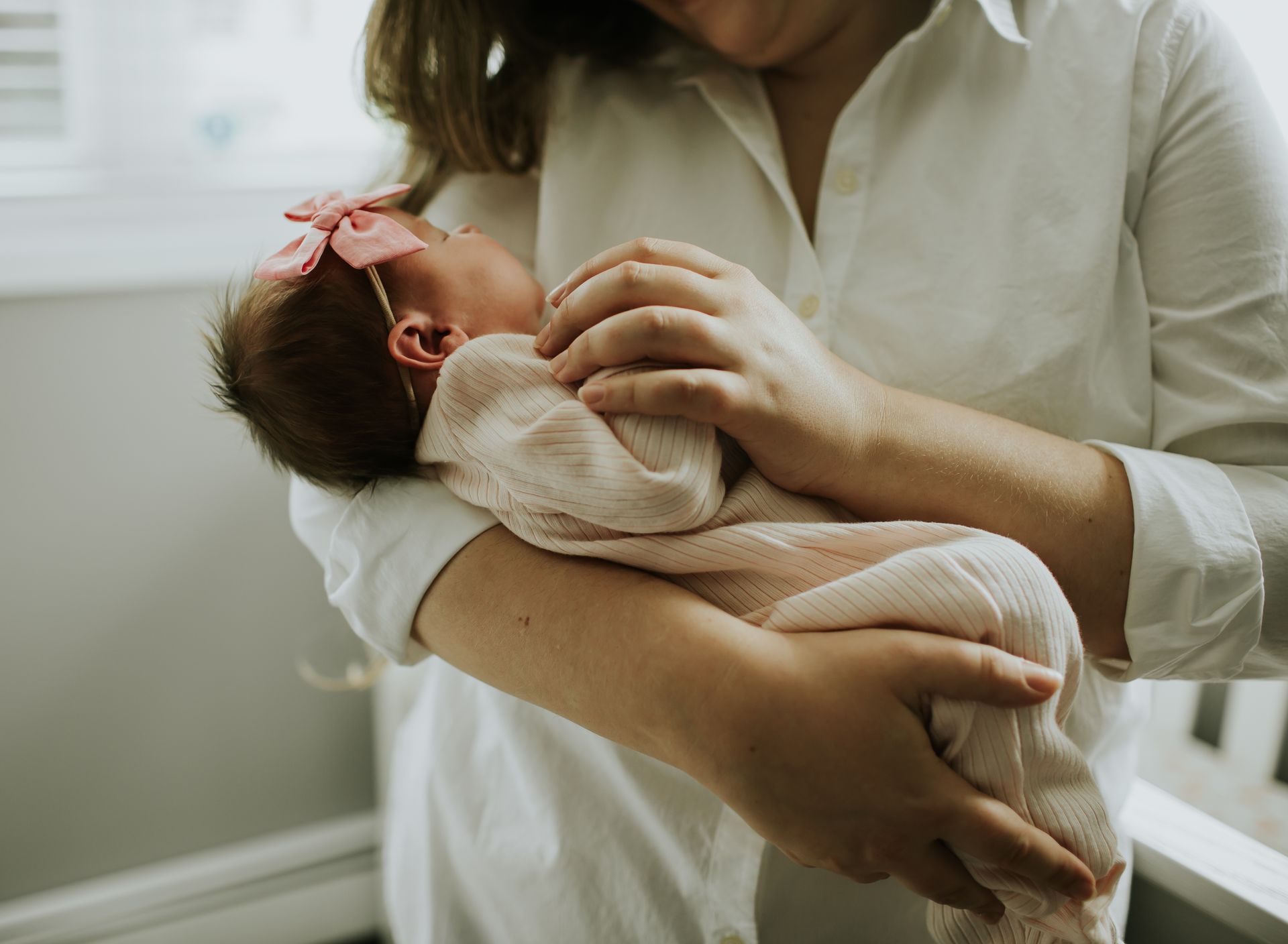 A woman is holding a baby girl in her arms in the nursery.