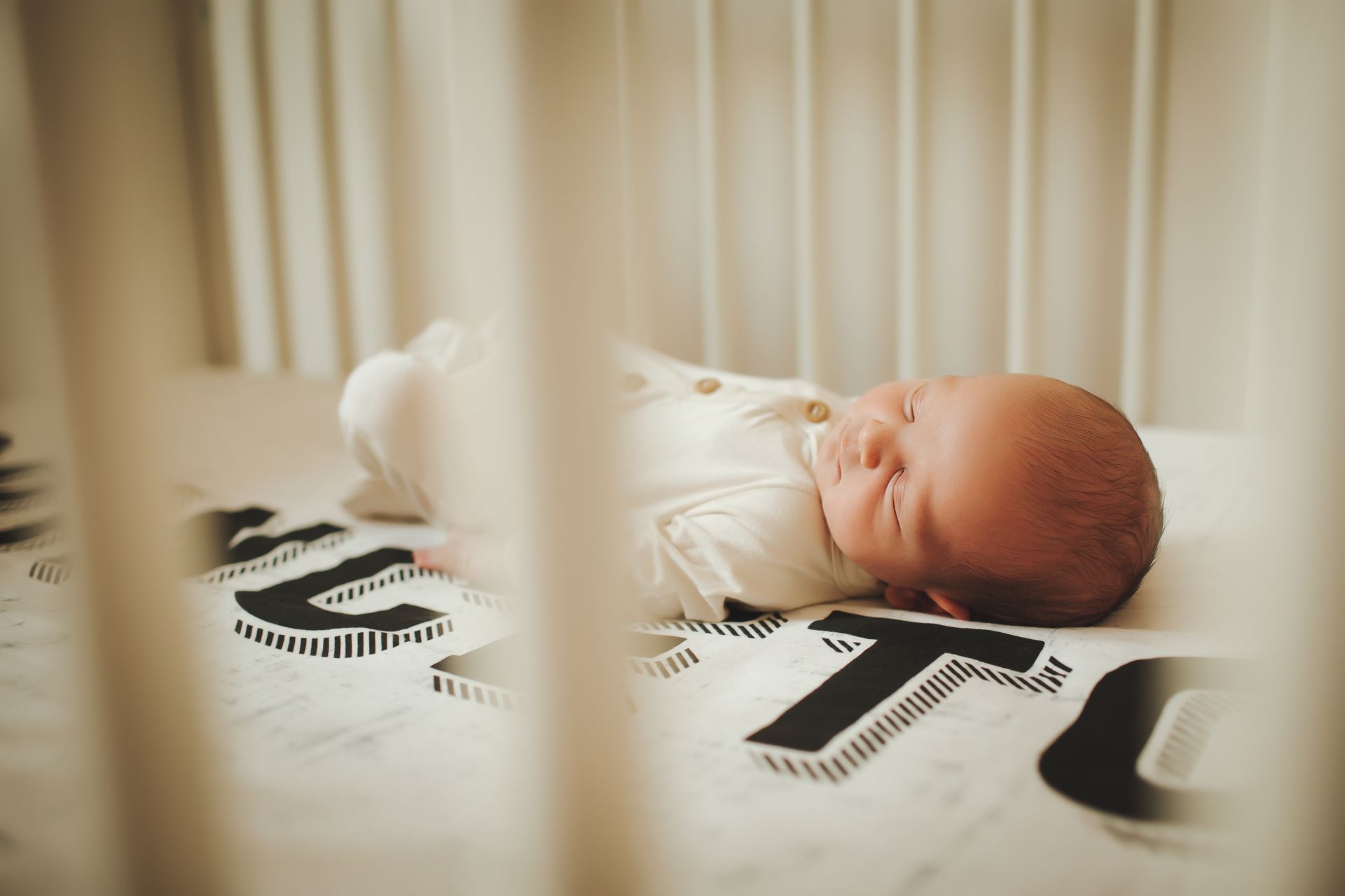 A newborn baby is sleeping in a crib.