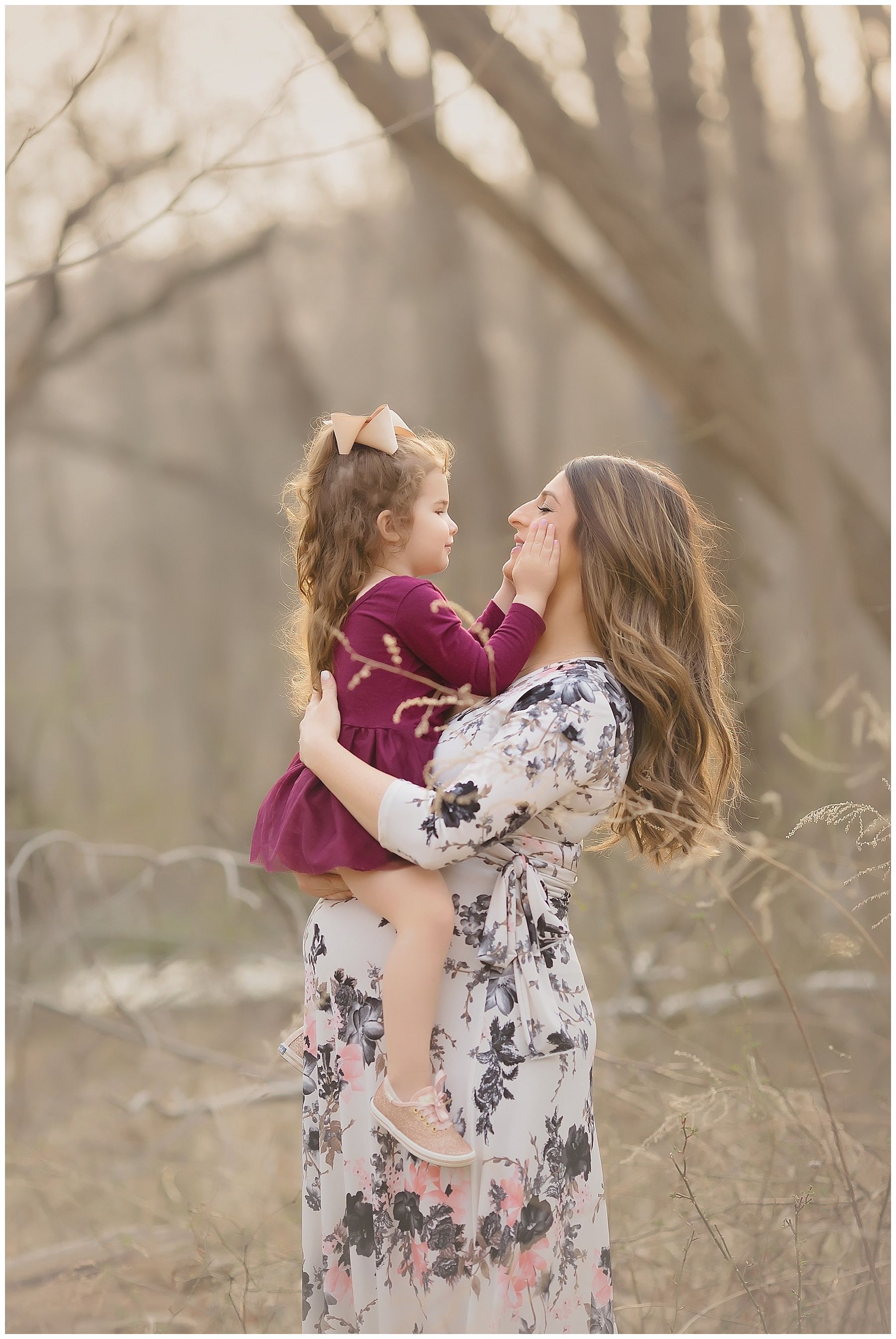 A woman is holding a little girl in her arms in a field.