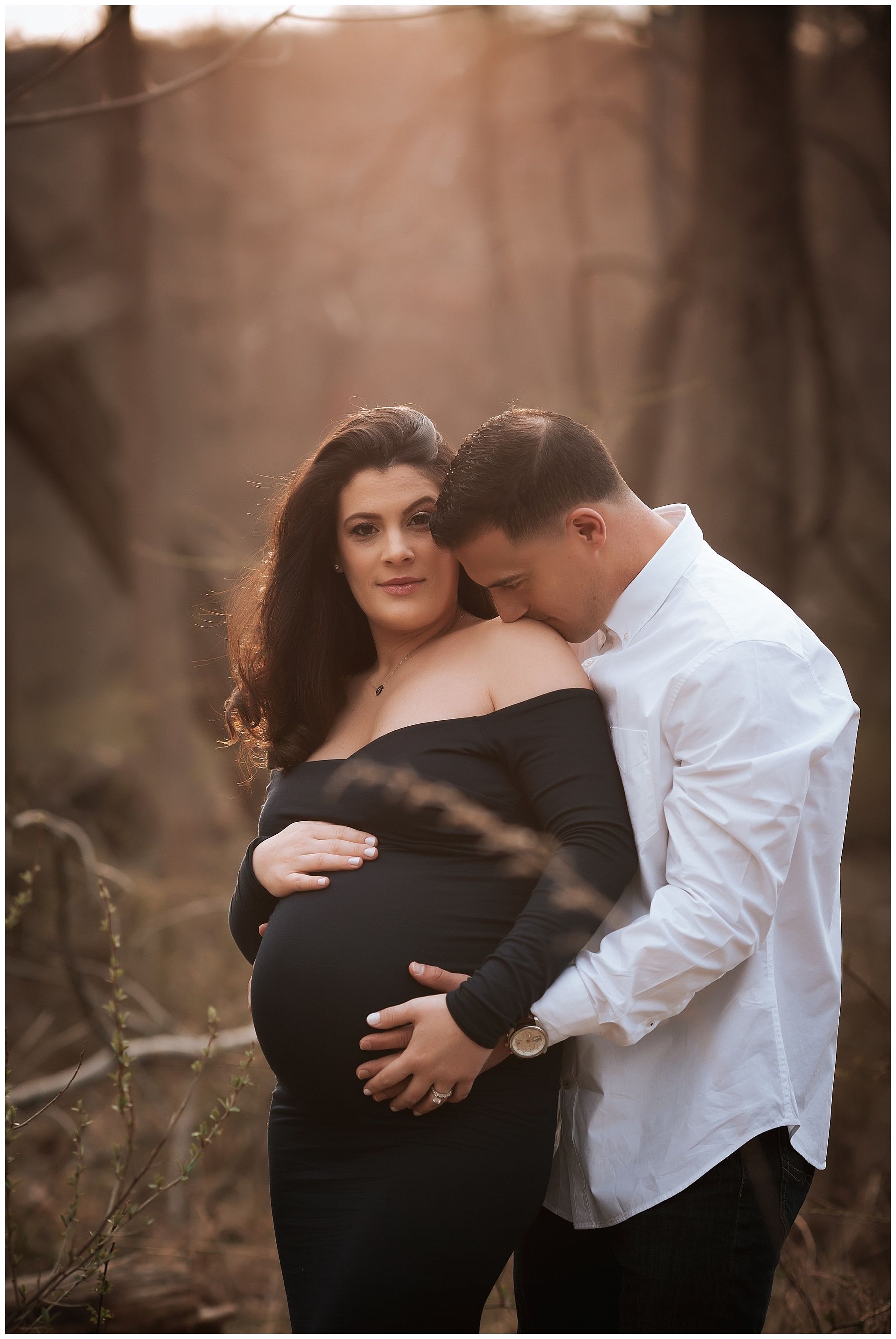 A pregnant woman in a black dress is standing next to a man in a white shirt.