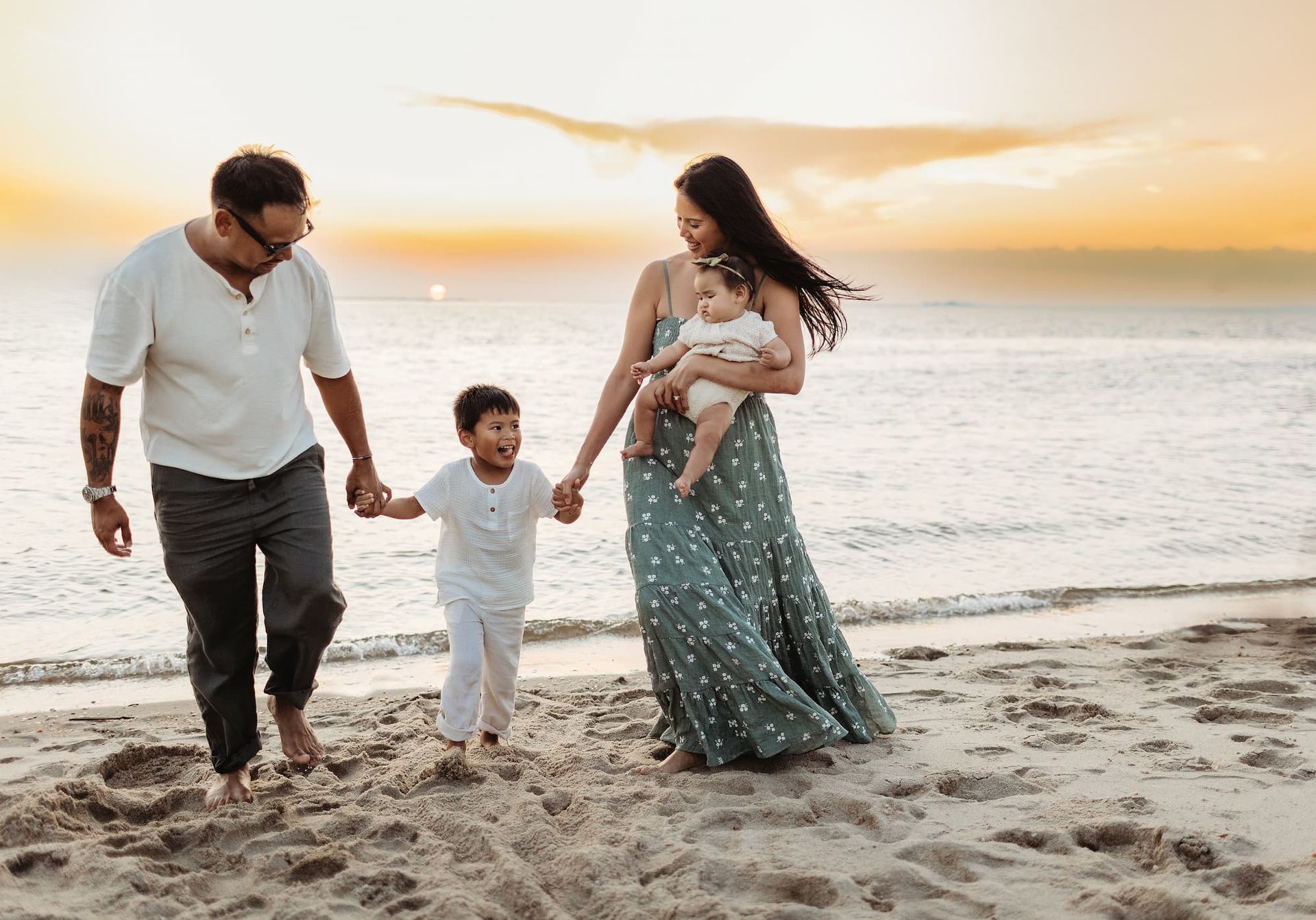 Family walking on beach at sunset, holding hands.