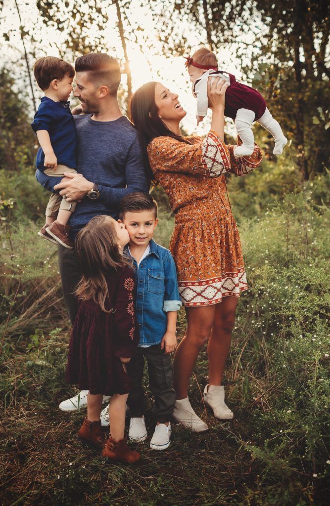 A family is posing for a picture in the woods.