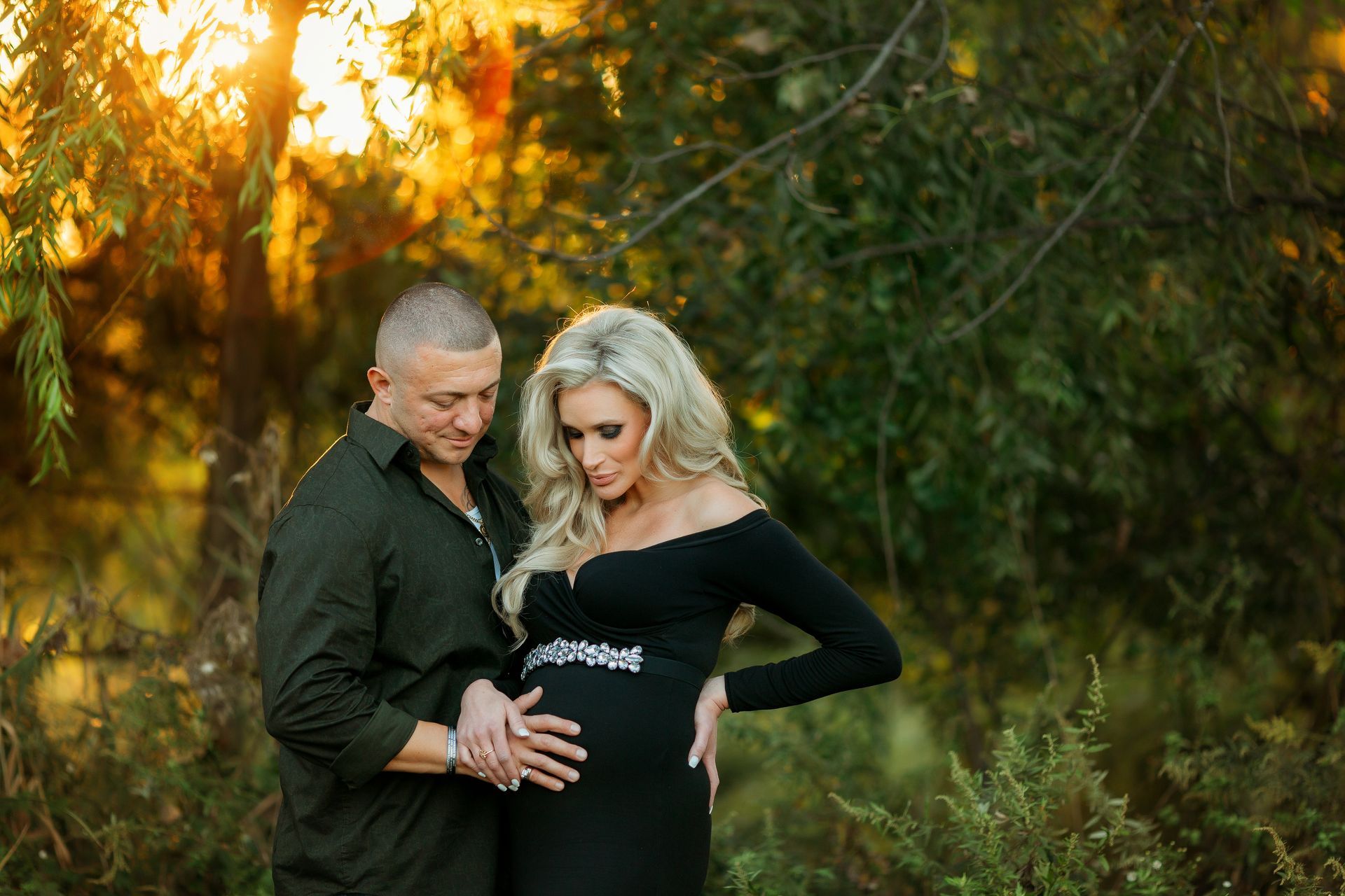 A man and a pregnant woman are posing for a picture in the woods in Leonia NJ