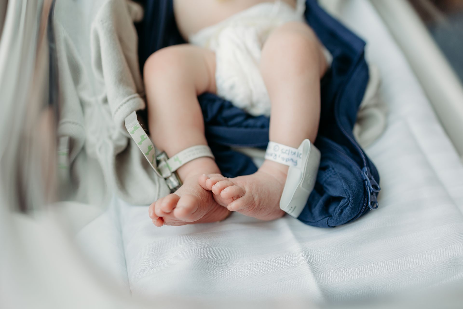 Man kissing newborn's feet, black and white photo. Baby in hospital clothes, father's face close.
