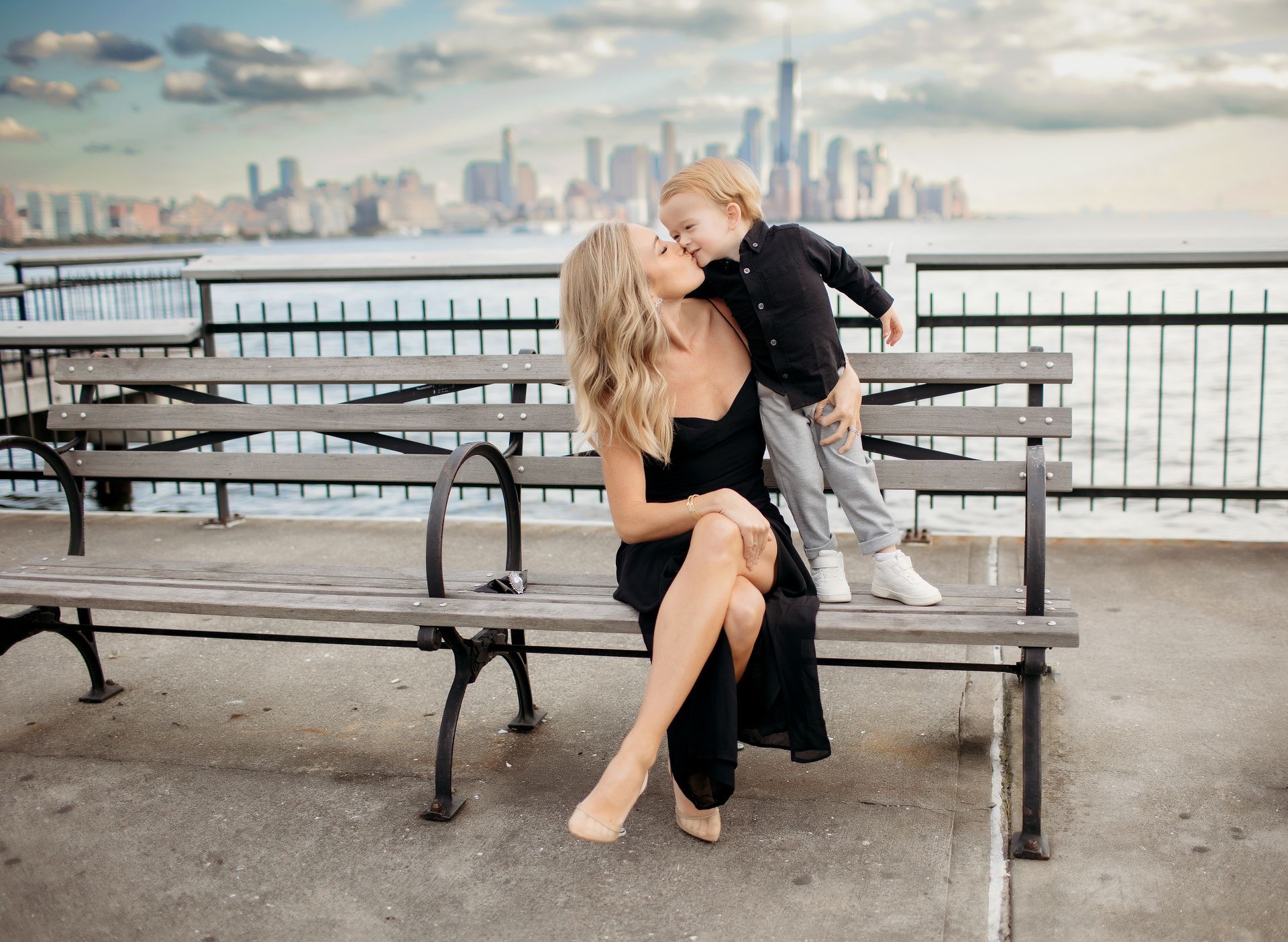 A woman and a child are sitting on a park bench.