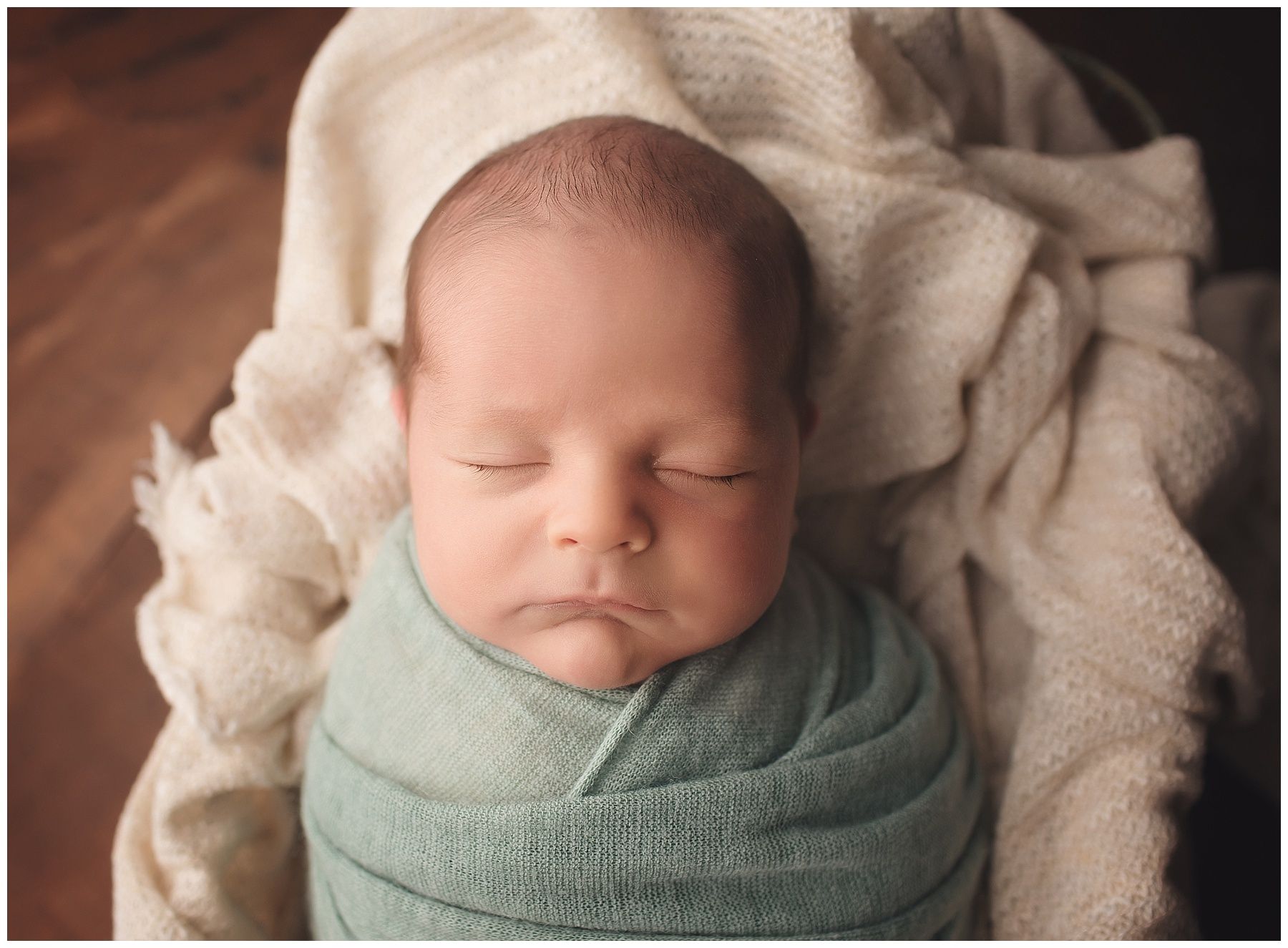 A newborn baby is wrapped in a white blanket and sleeping.