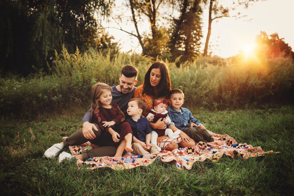 A family is sitting on a blanket in the grass.
